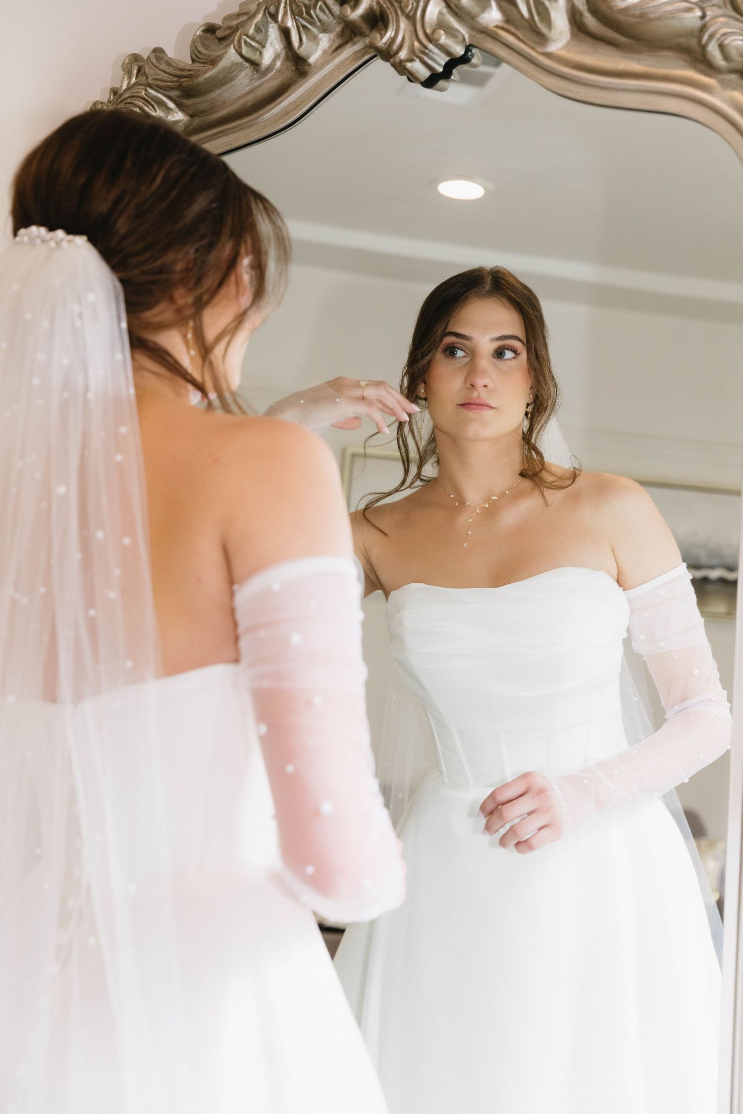 Elegant off-shoulder white wedding dress with delicate details shown from multiple angles in a bridal fitting room.
