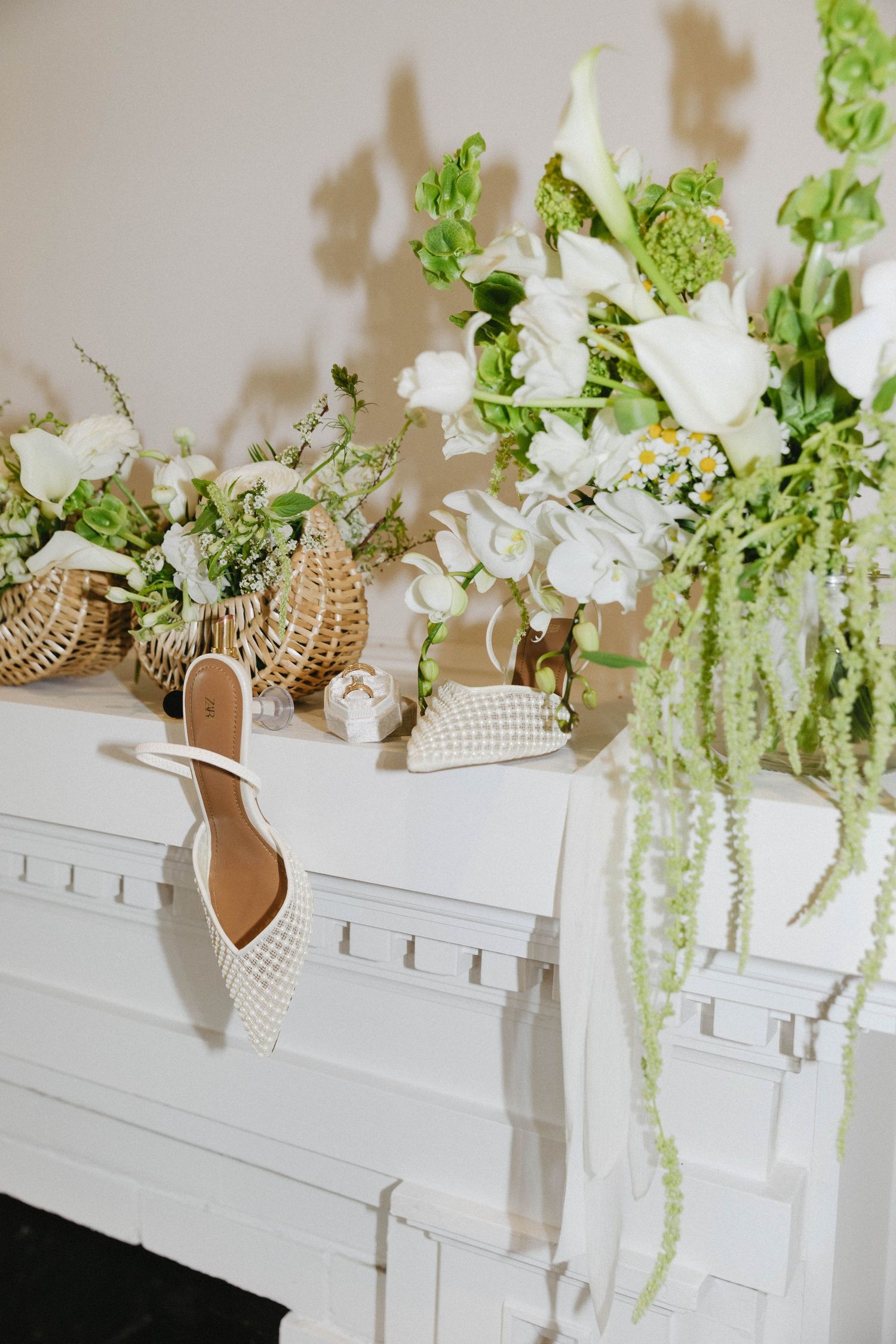 Elegant white floral arrangements with cascading greenery displayed on a classic white mantelpiece.
