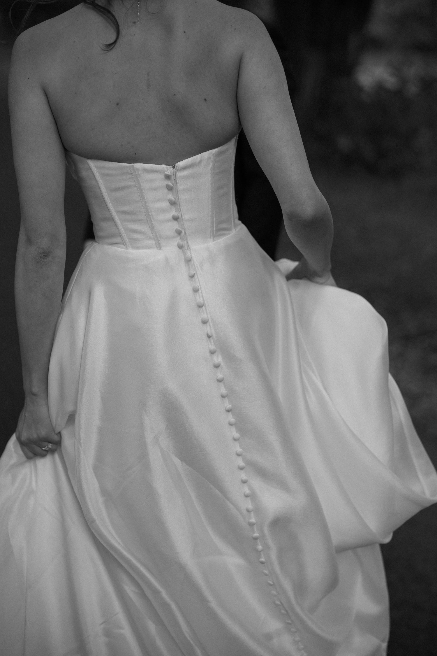 Detail shot of wedding dress back showing elegant button closure and flowing skirt.