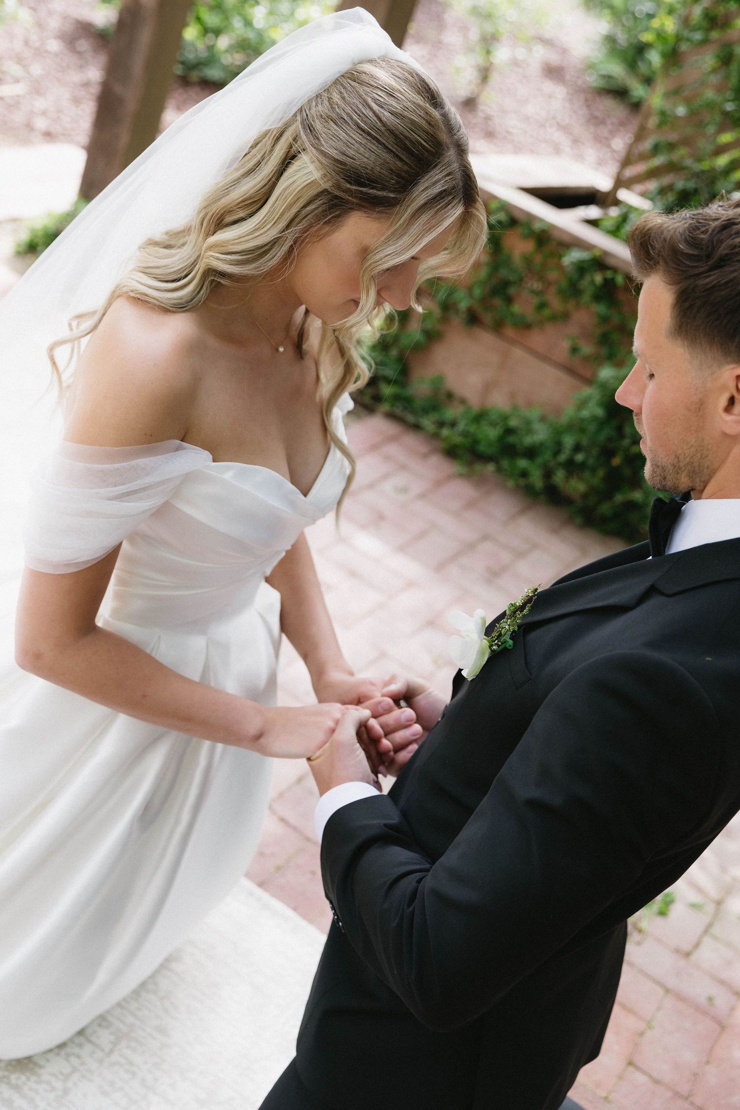 Tender moment during wedding ceremony as couple exchanges rings under covered patio.