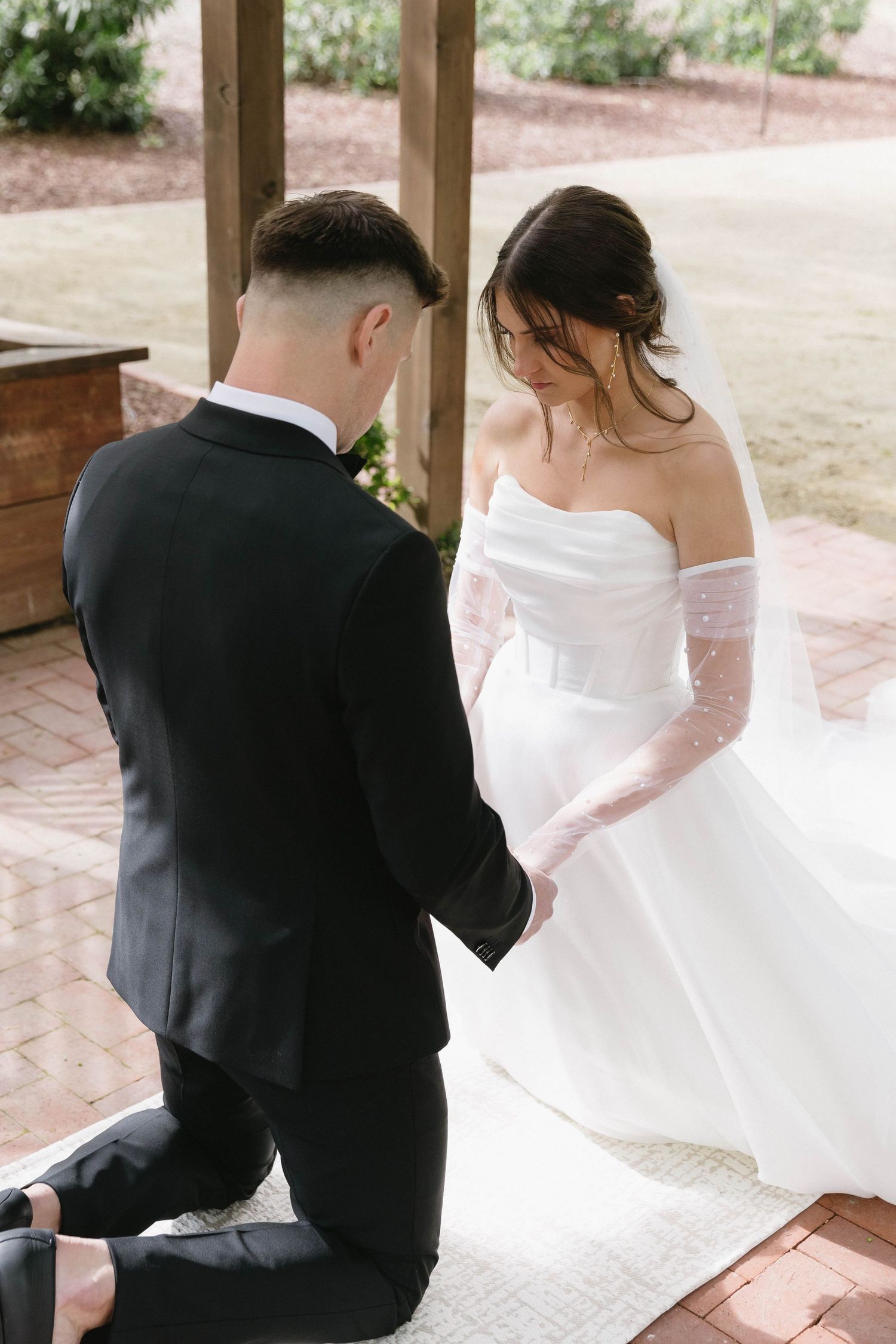 Intimate wedding ceremony moment under wooden pergola with couple exchanging vows.
