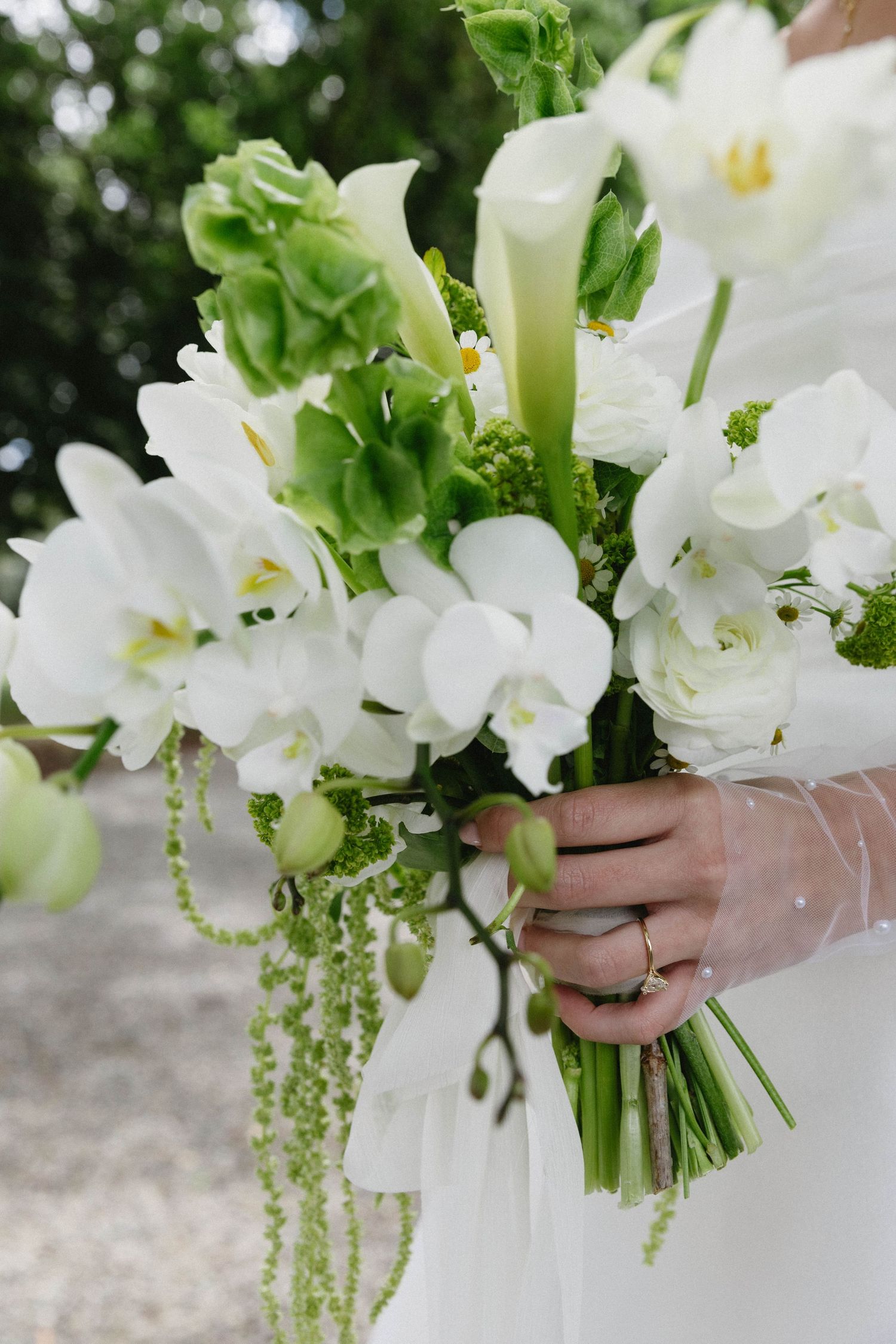 Close-up of an elegant white and green bridal bouquet with cascading elements.