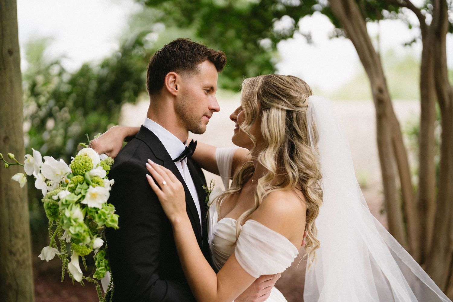 Wedding couple embracing in an outdoor garden setting with lush greenery.
