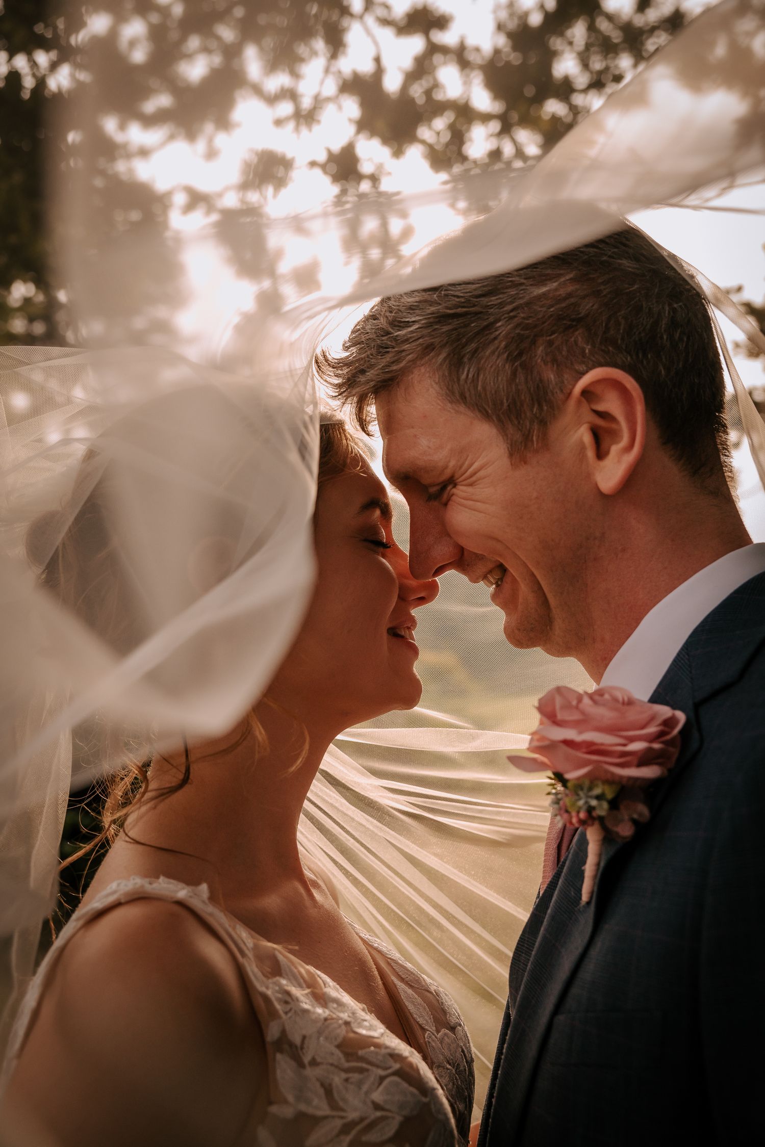 Romantic close-up of couple sharing intimate moment under flowing veil.