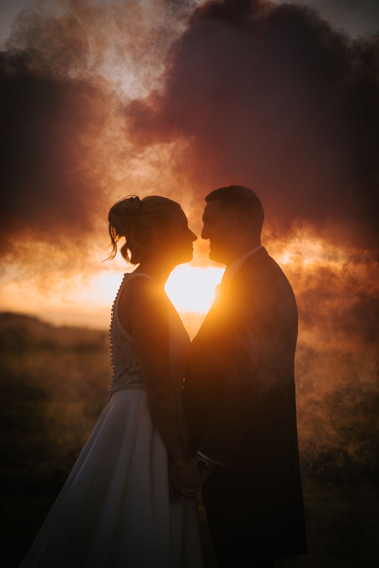 Silhouette of couple against dramatic orange sunset sky.