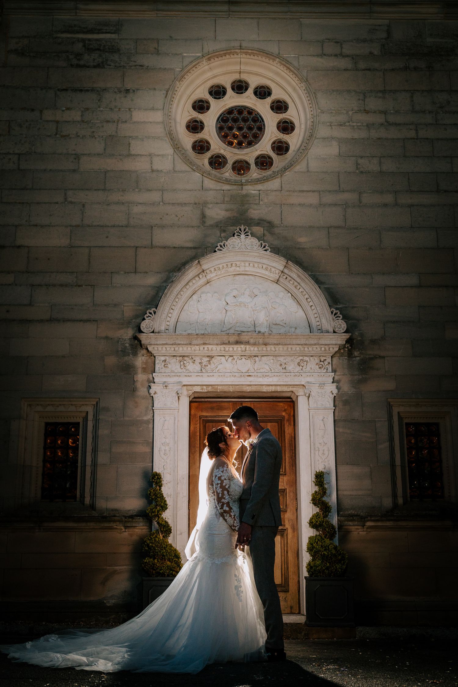 Romantic wedding portraits captured against gothic stone architecture at dusk.