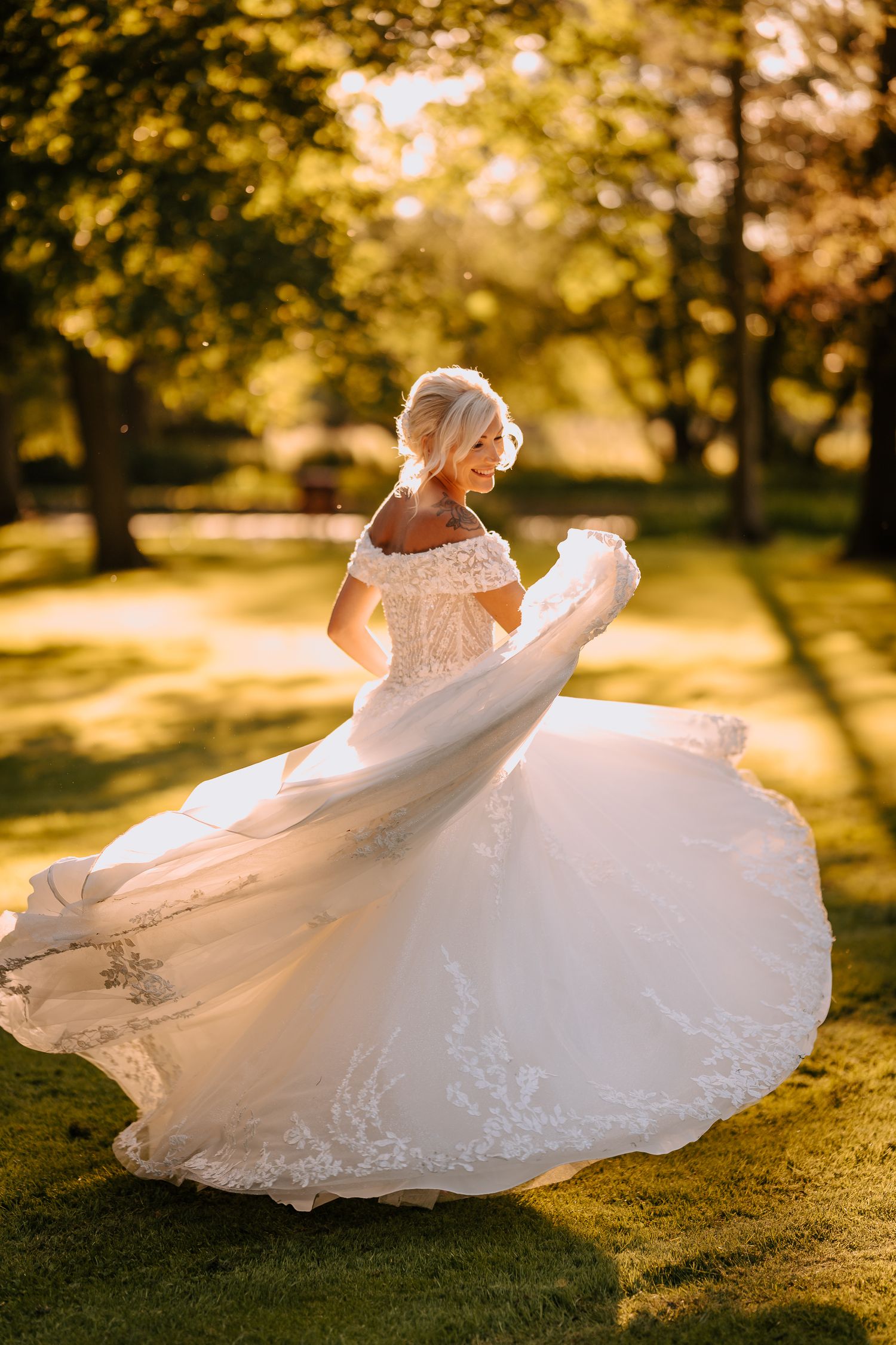A bride twirling in a flowing white dress during golden hour in an orchard.