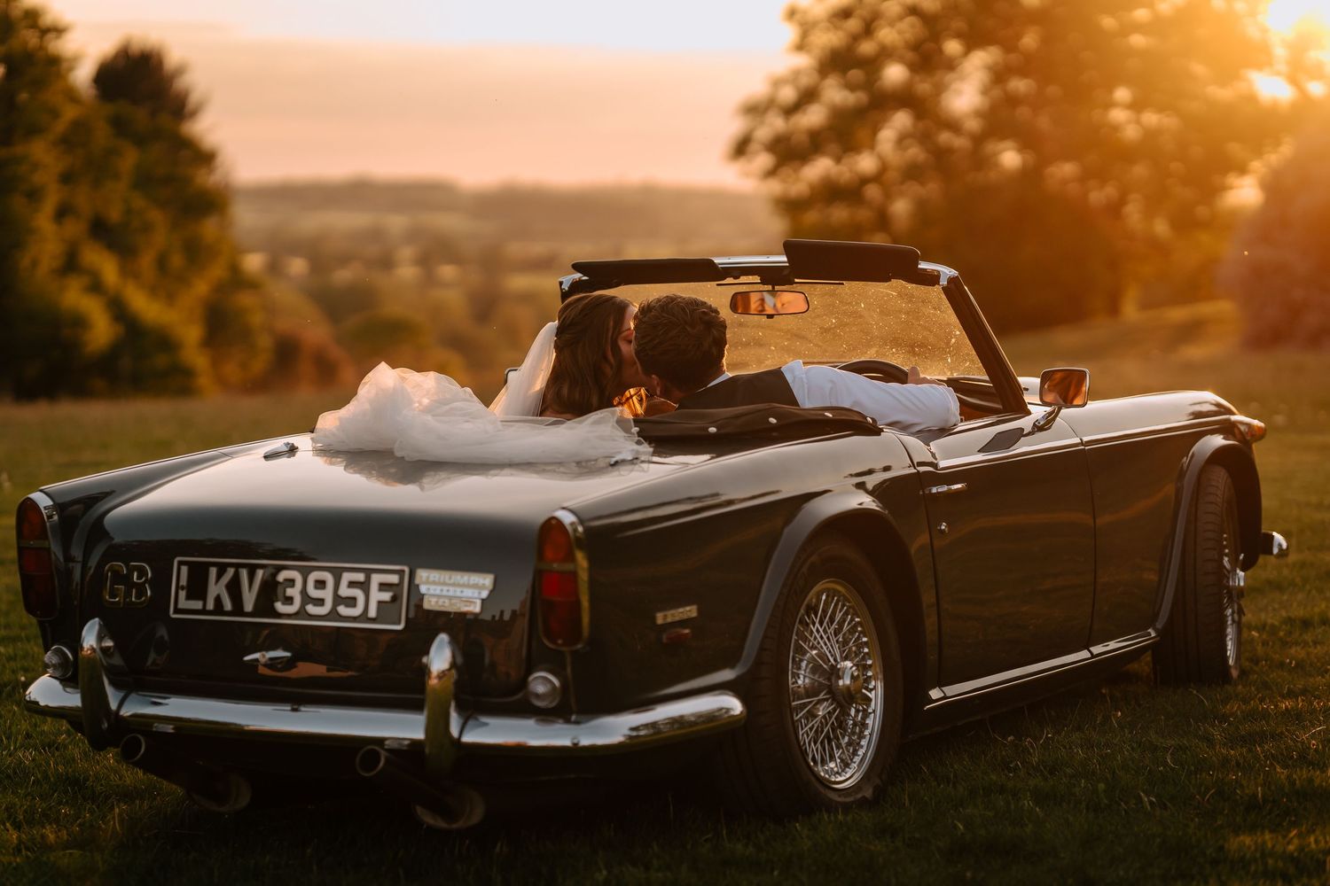 Classic vintage convertible car parked on a hill at golden sunset.
