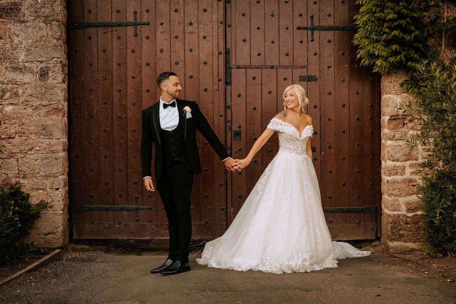 A rustic wedding photoshoot against weathered wooden doors and brick walls.