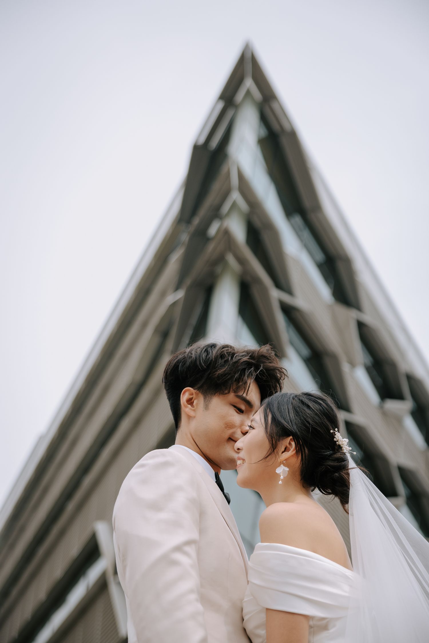 An elegant wedding portrait in front of a modern geometric church building.