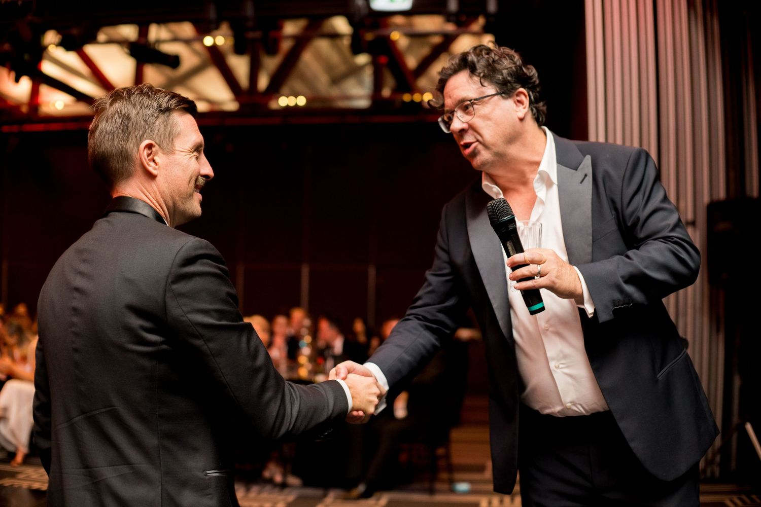 candid photo of 2 men having a handshake during a corporate event in sydney by sam haber