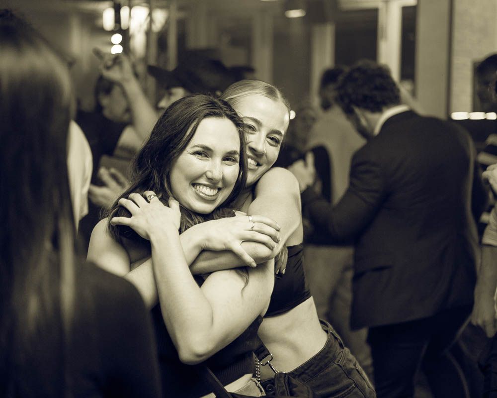 candid photo of two friends hugging during nightlife party in sydney by sam haber