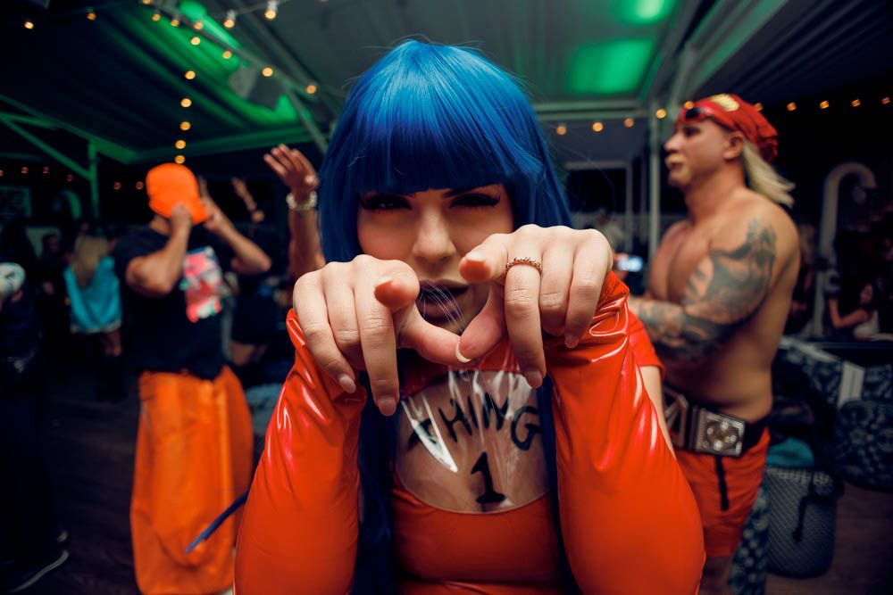 candid photo of a woman pointing to the caemra wearing a blue wig during nightlife party in sydney by sam haber