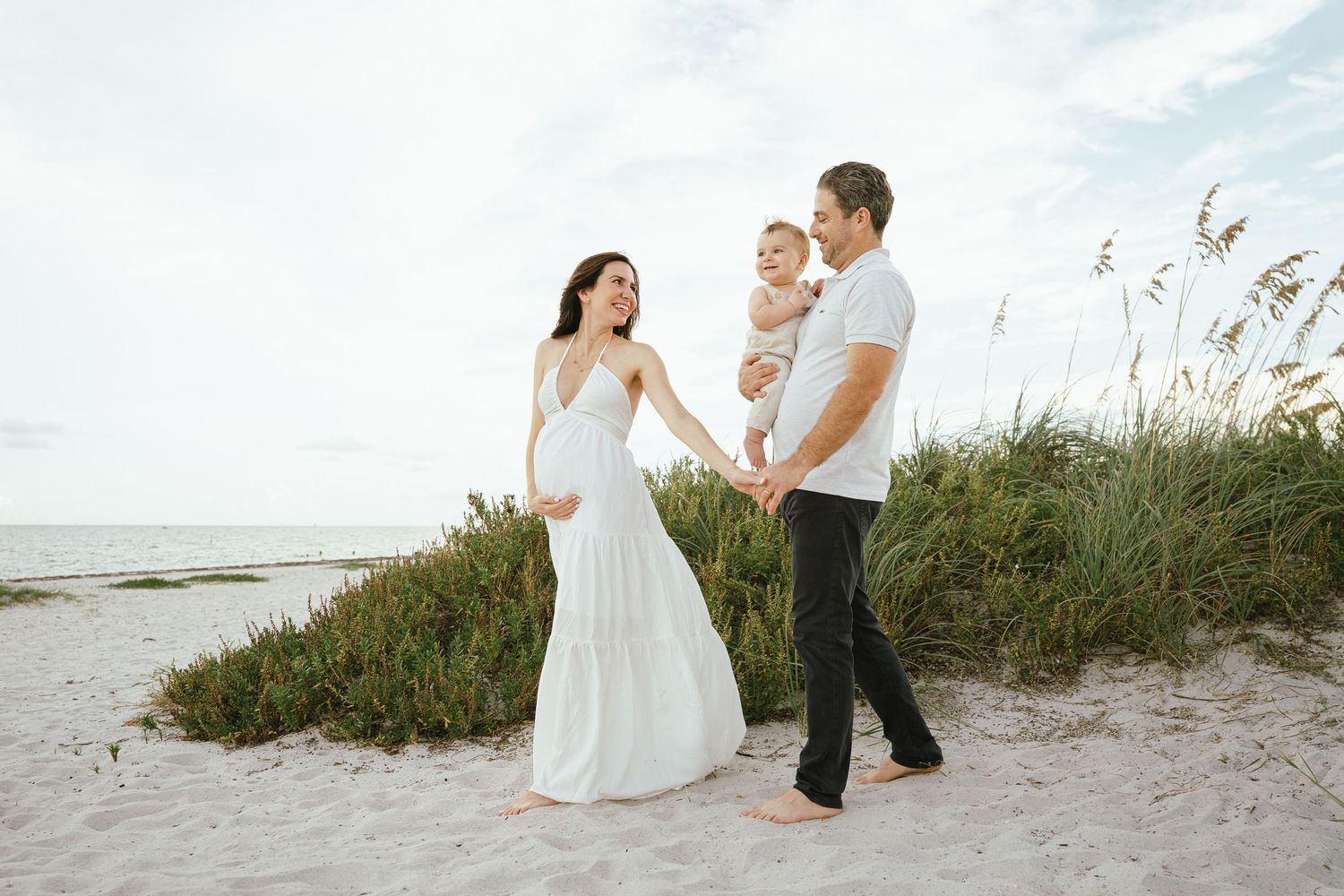 A family shares tender moments together on a sandy beach during sunset.