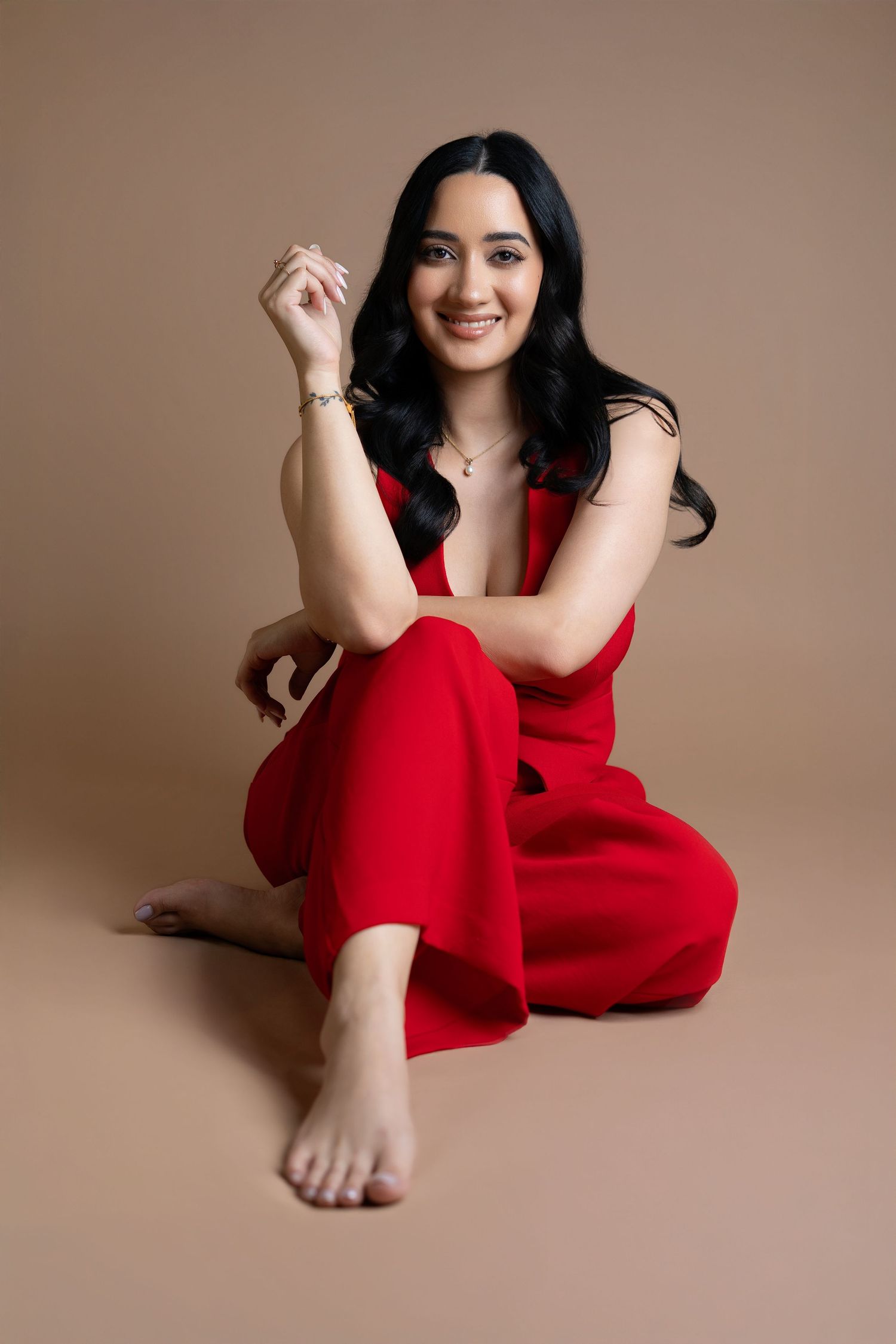 Relaxed portrait session in red dress against neutral backdrop.
