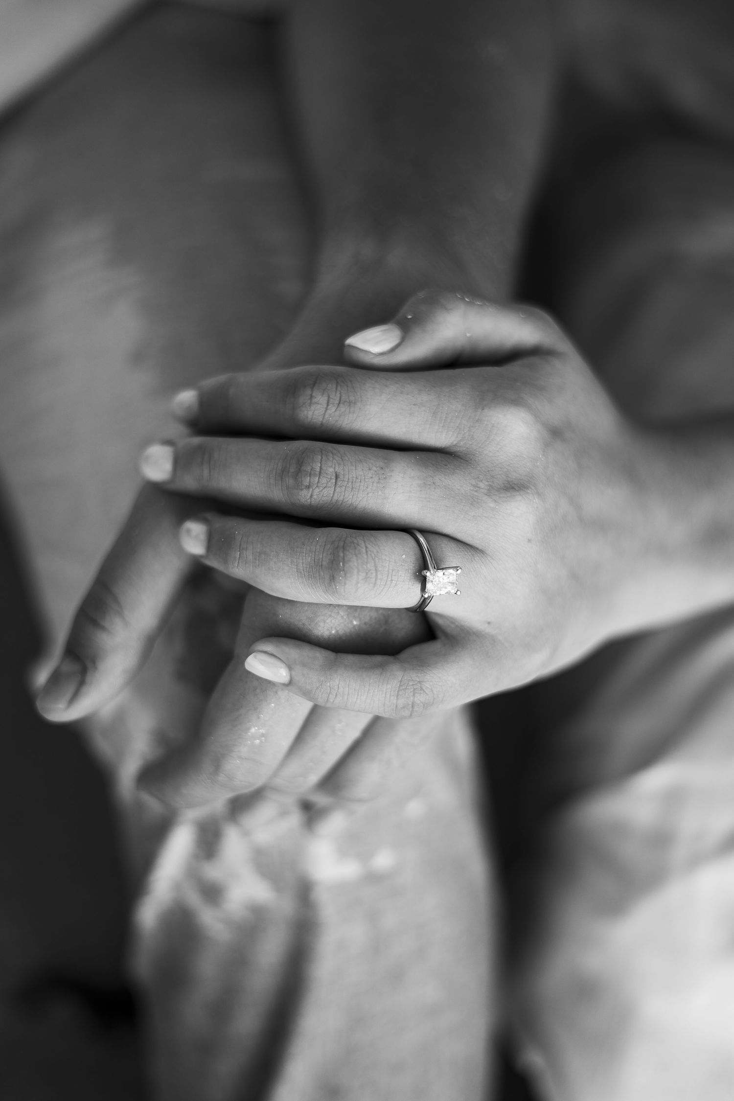 Close up black and white photo of hands with an engagement ring.