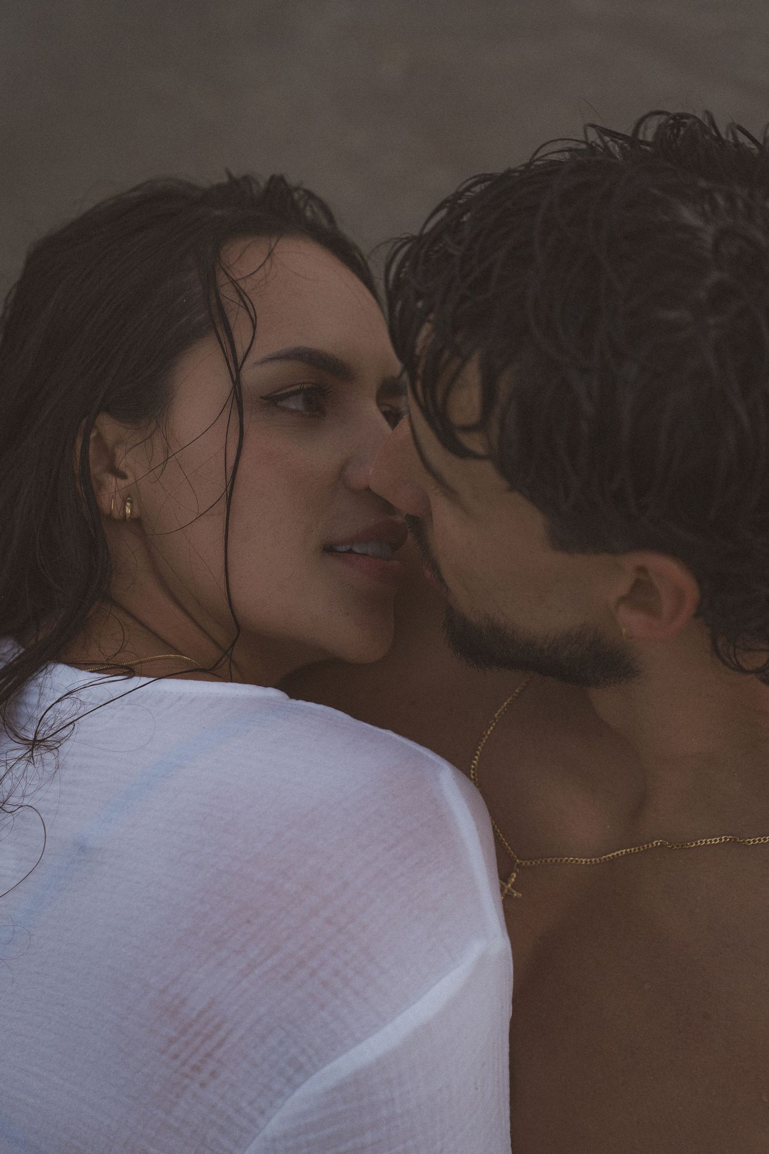 Intimate close-up portrait of couple sharing romantic moment against dark background.