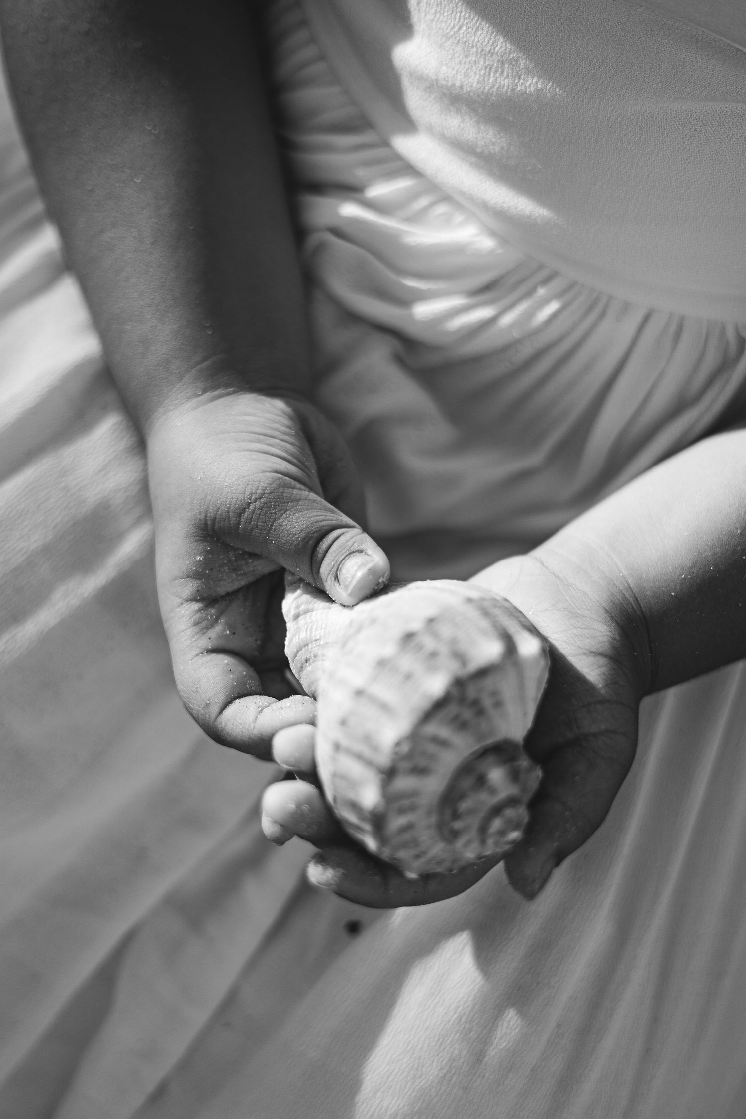 Close-up black and white detail of hands holding fabric of white dress.