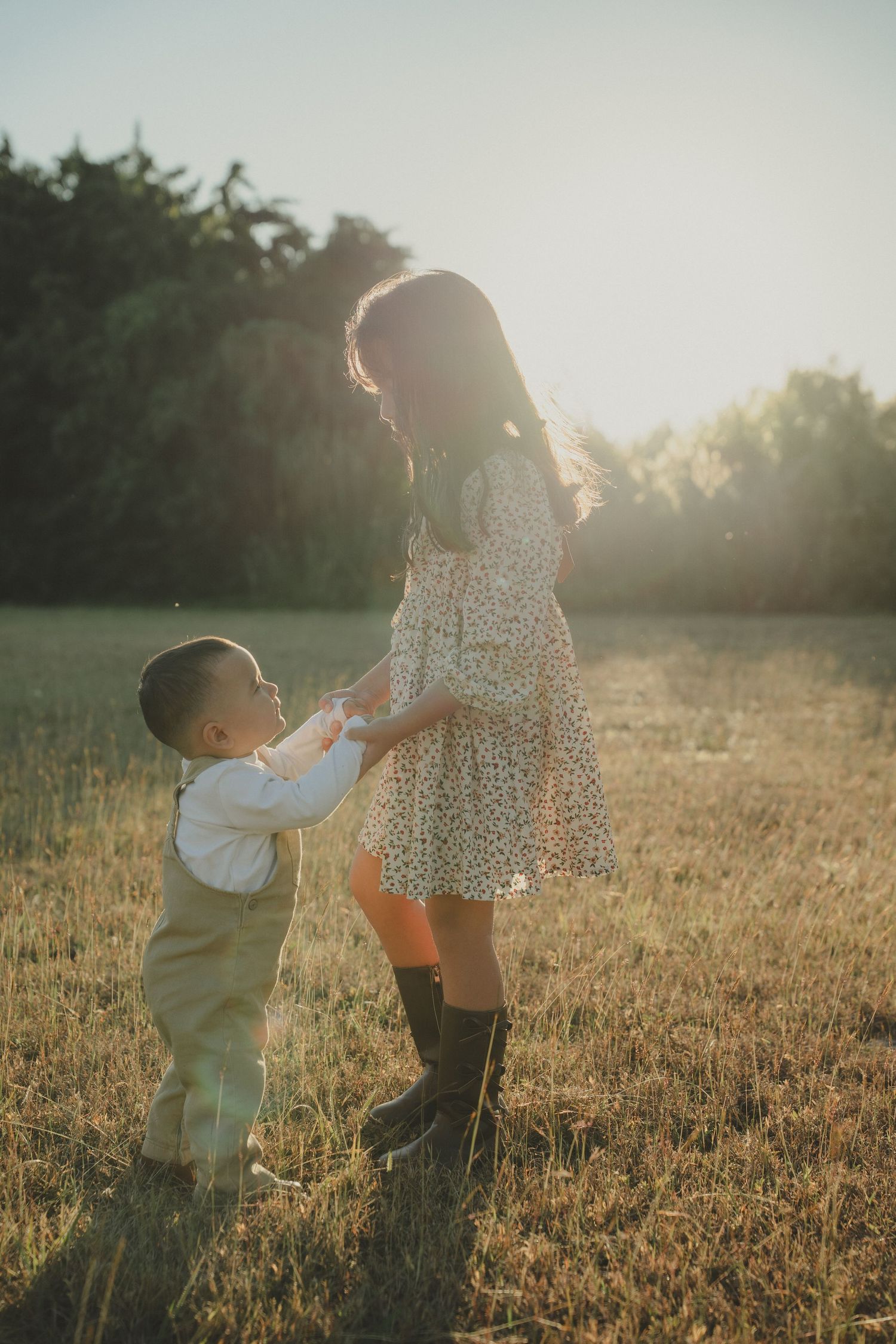 Family enjoying a tender moment together in a sun-drenched field at sunset.