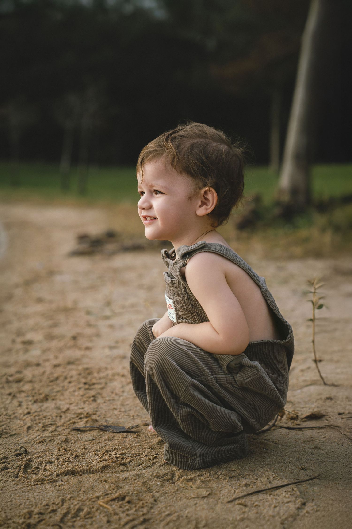 Young child playing on sandy ground in natural outdoor lighting.