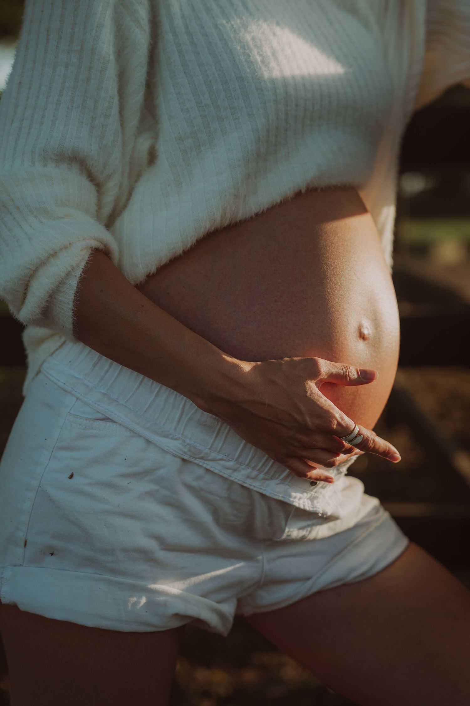 Close-up artistic shots of pregnant belly in natural window light.