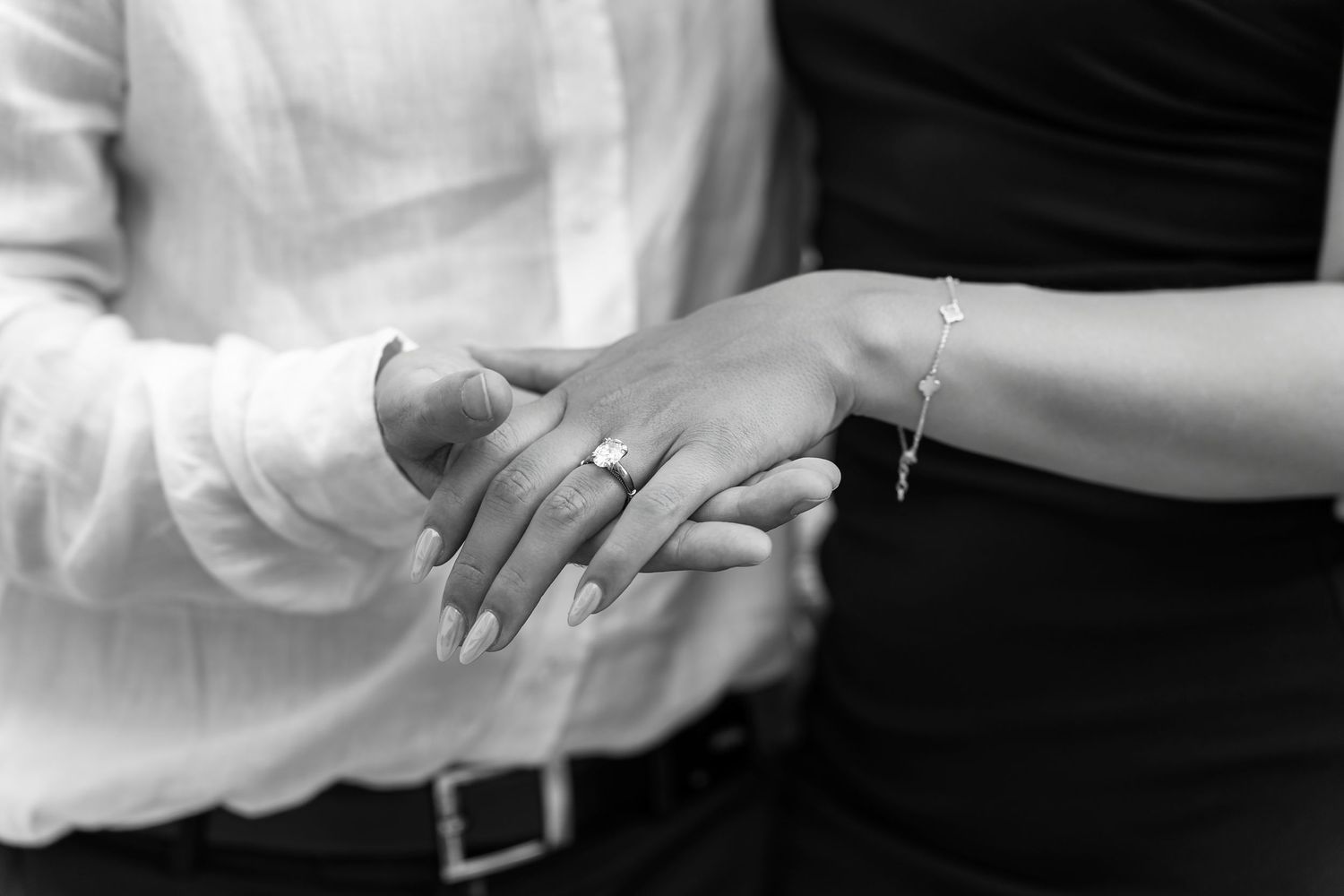 Close-up black and white photo of hands exchanging rings during a wedding ceremony.