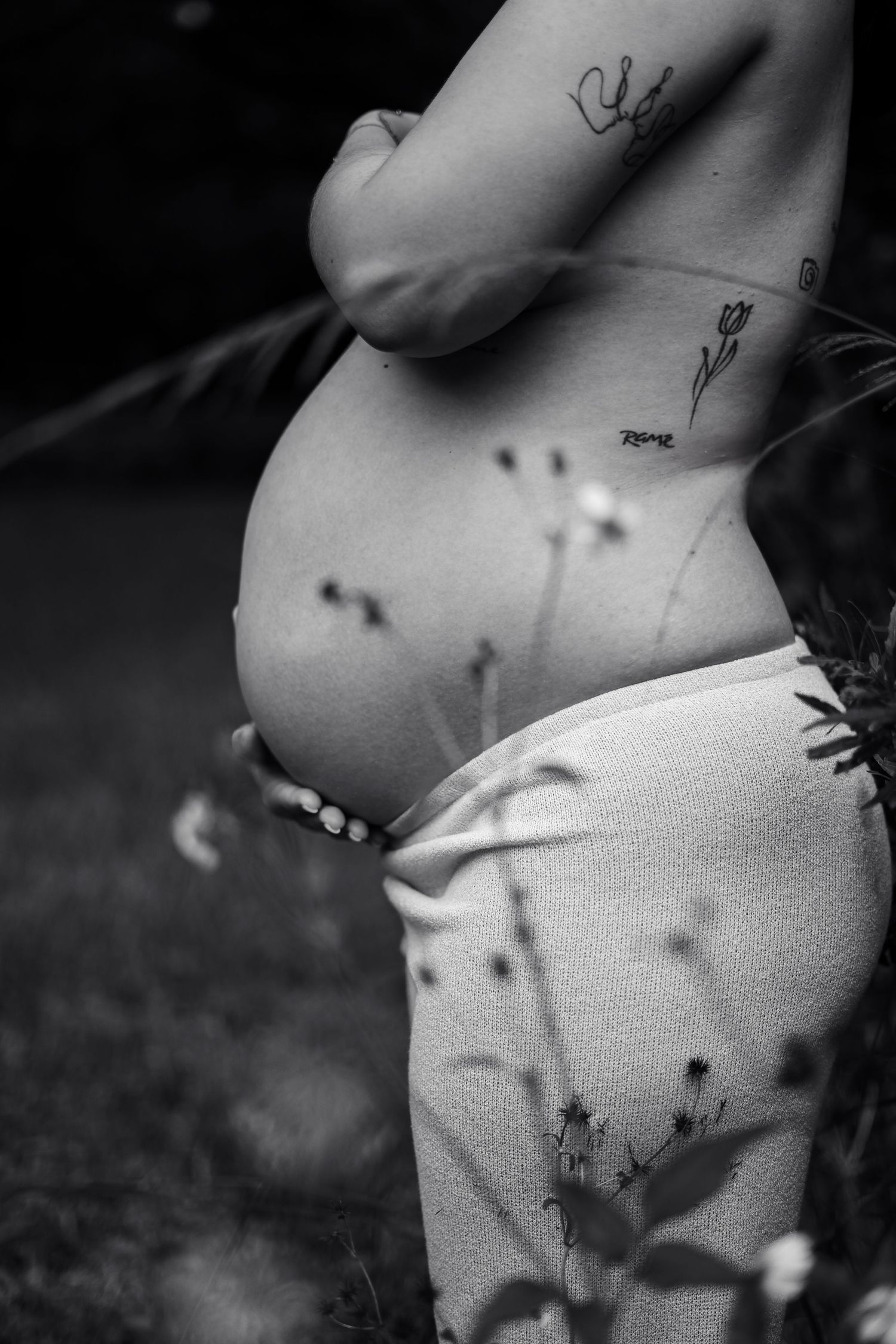 Black and white artistic close-up of pregnant belly with shadow patterns.