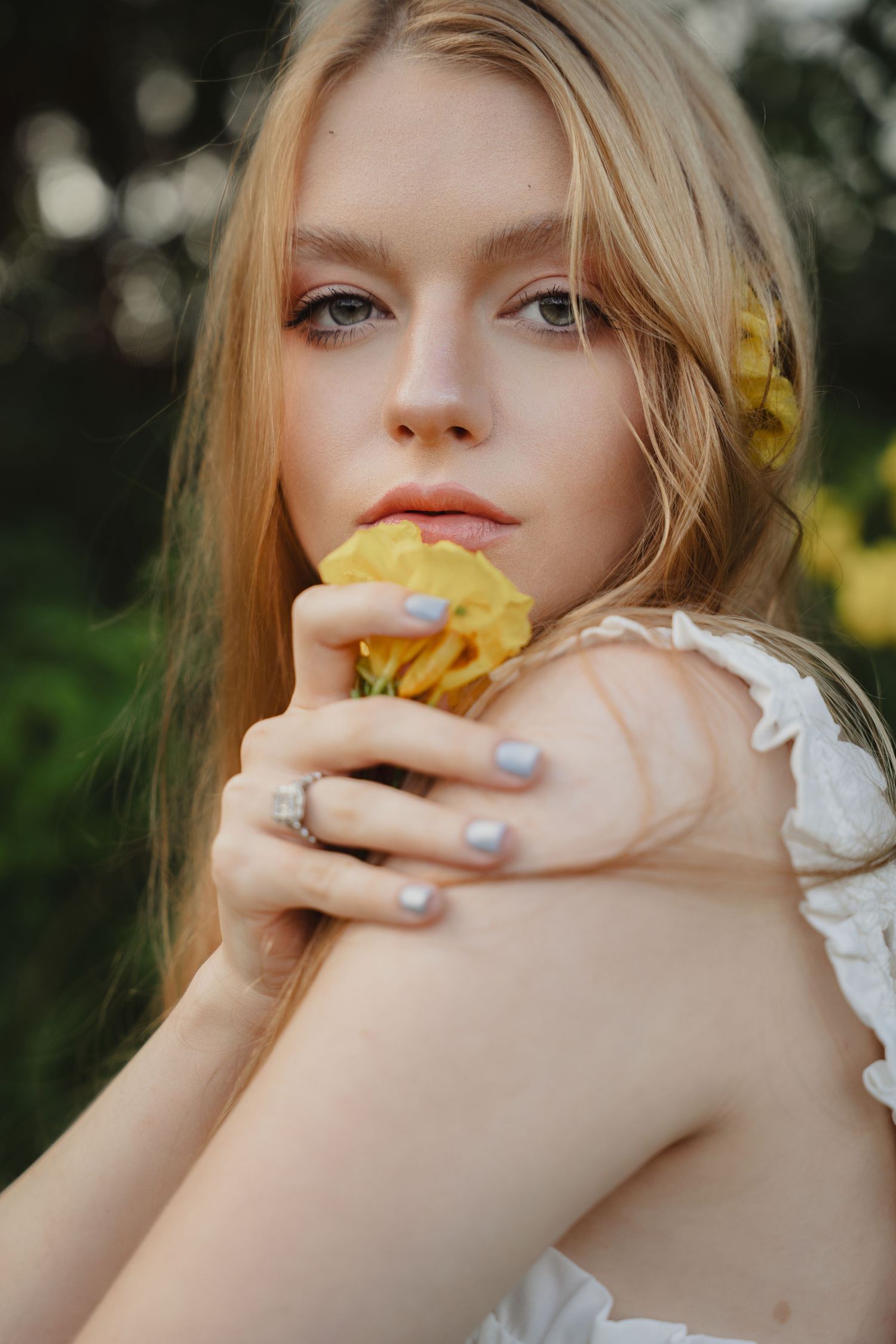 Artistic close-up portrait with yellow flowers and soft natural lighting.
