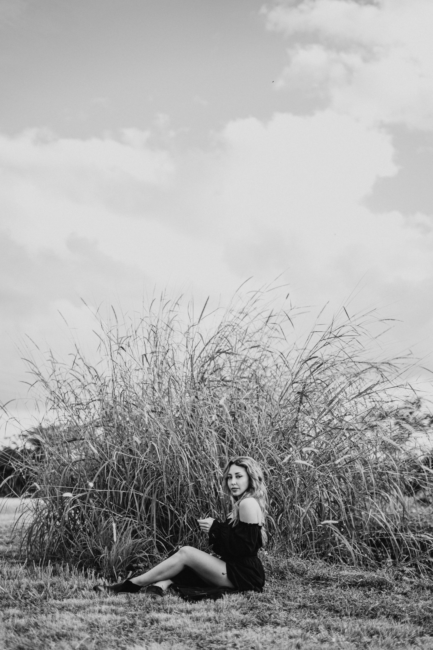 Black and white landscape photo with tall grass and reclining figure in natural setting.