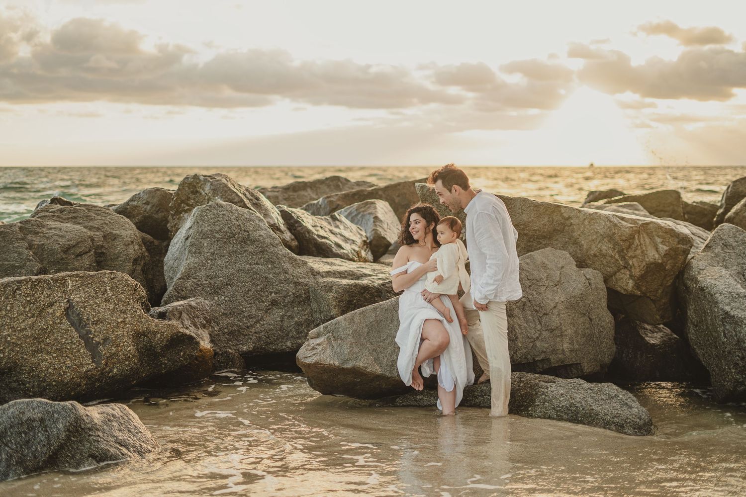 Sunset beach photography session among large rocky formations near ocean.