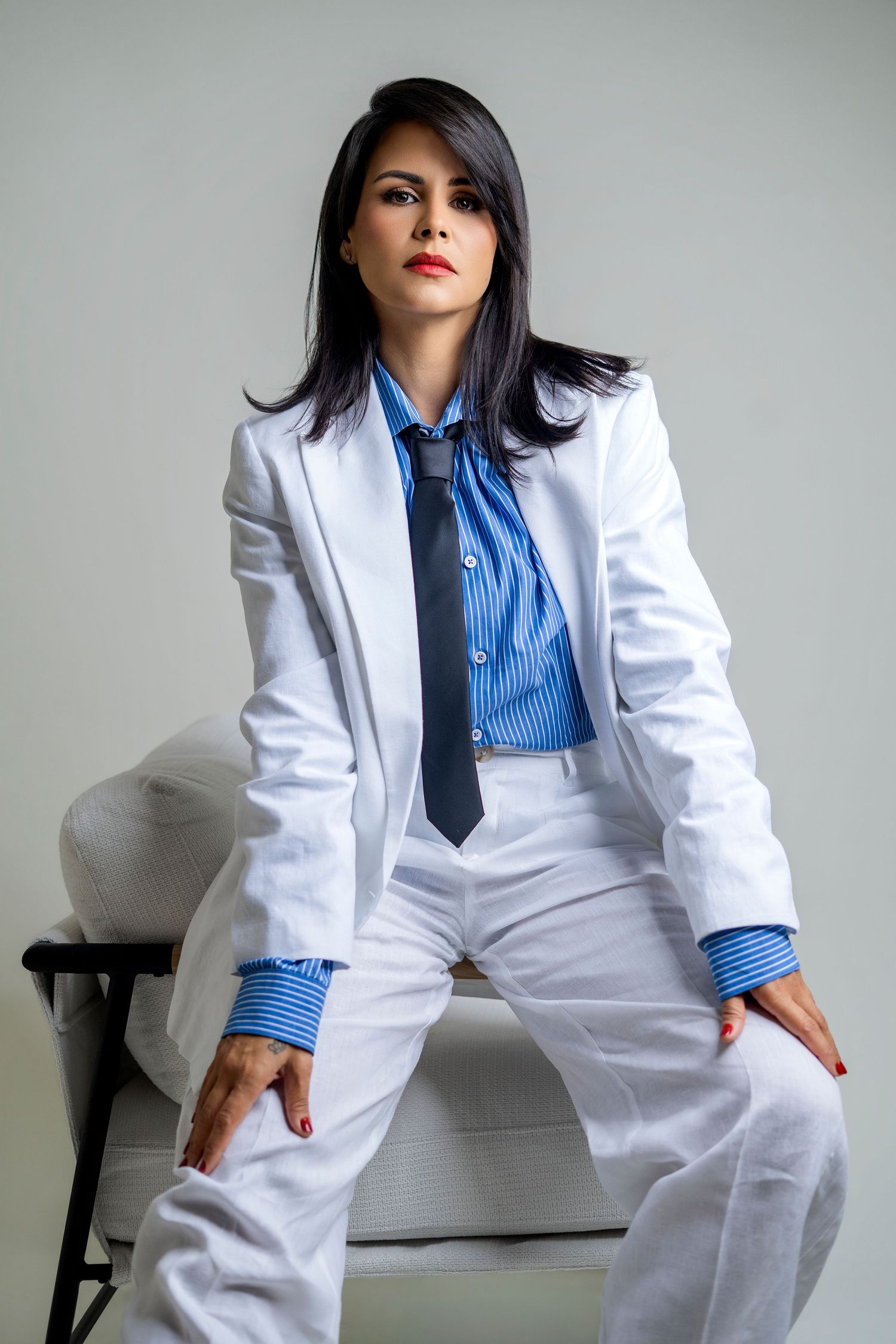 Fashion portraits in white suit and blue shirt showing confident poses against grey background.