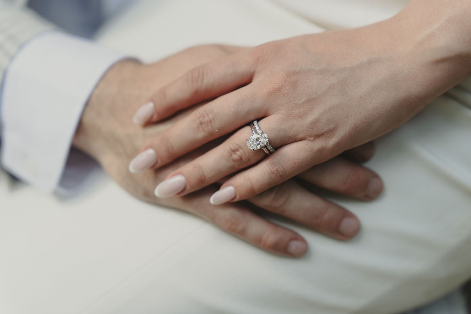 Close-up of a couple's hands with a sparkling diamond engagement ring and wedding band on the bride's finger.