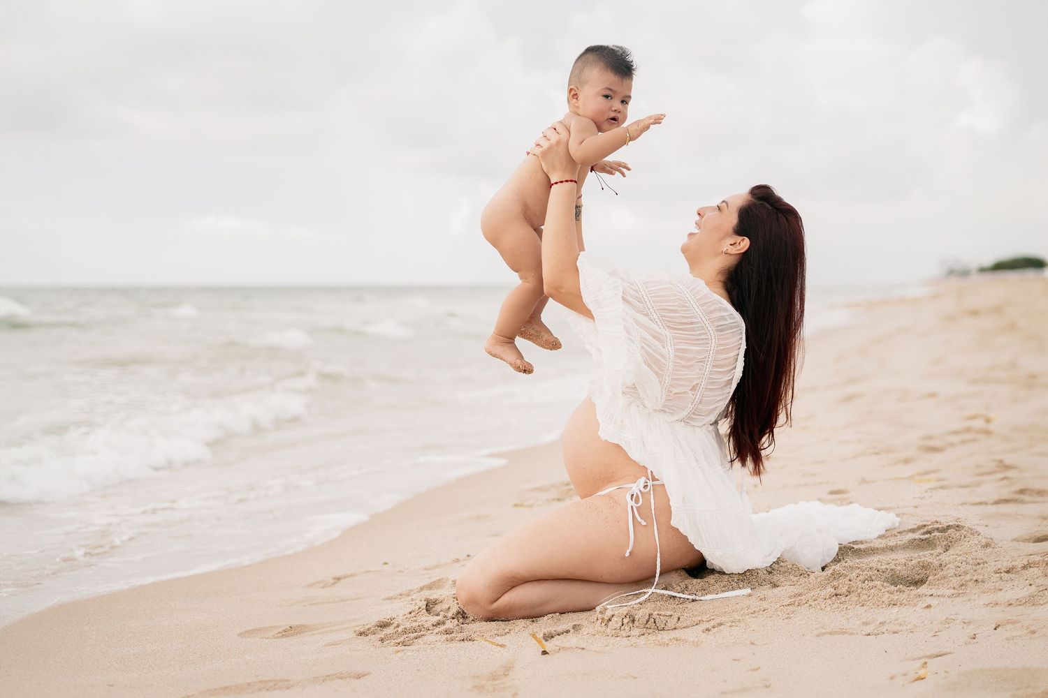 Family members play and laugh together on a sunny beach.