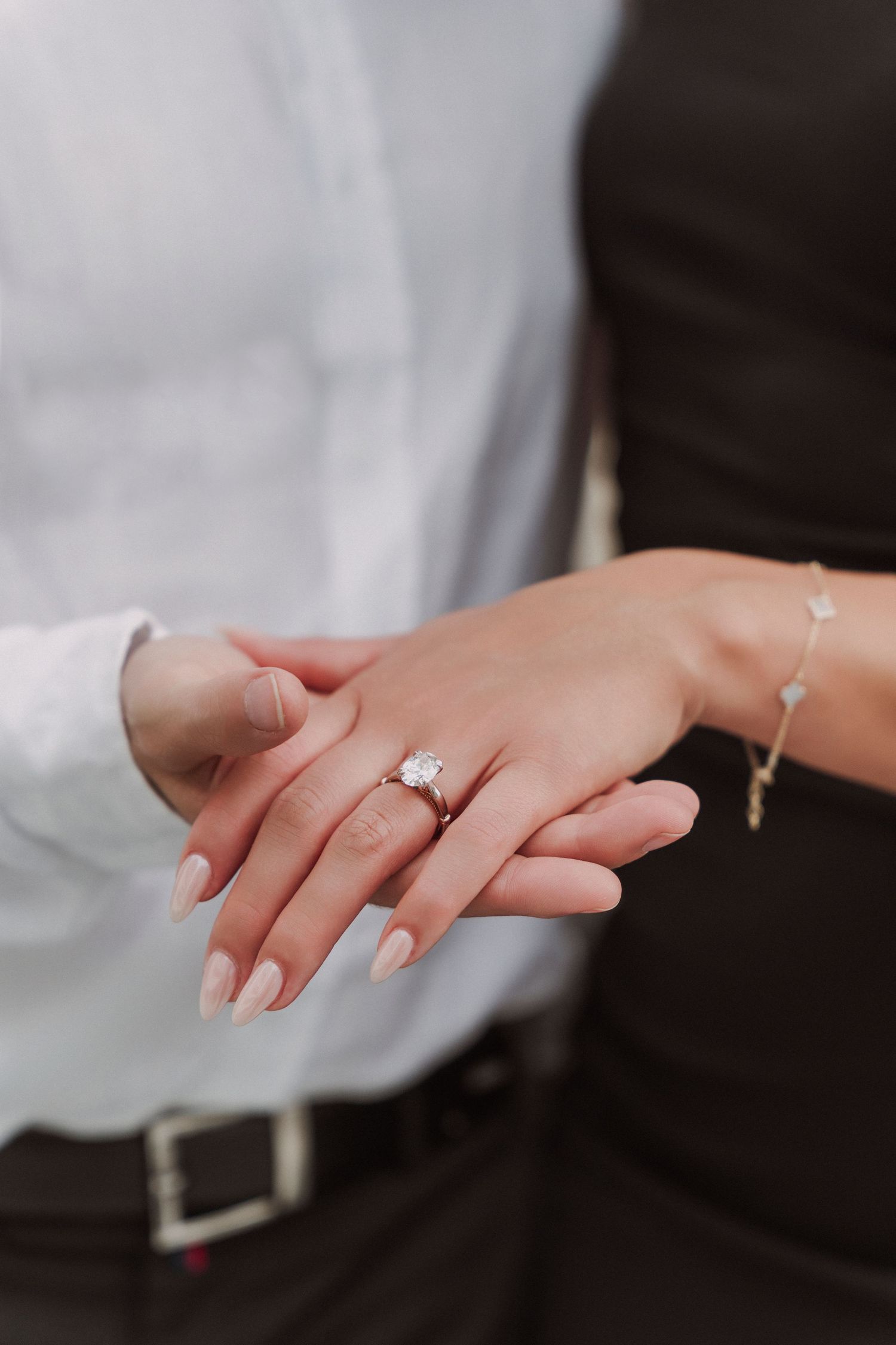 Close-up series of hands displaying a sparkling engagement ring.