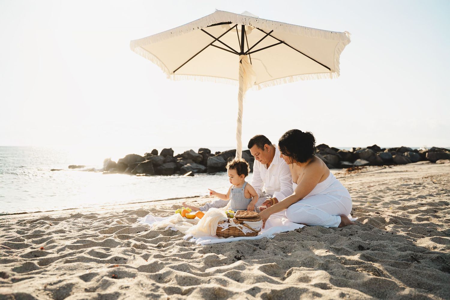 White beach umbrella provides shade during seaside family picnic.