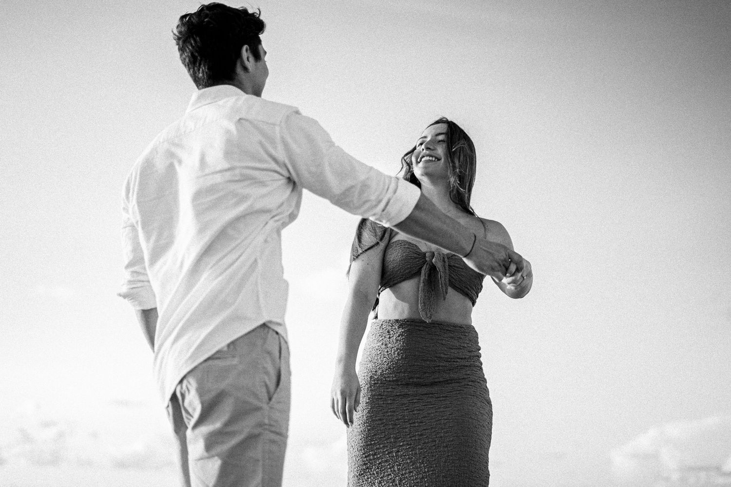 A couple dances together on the beach in black and white.