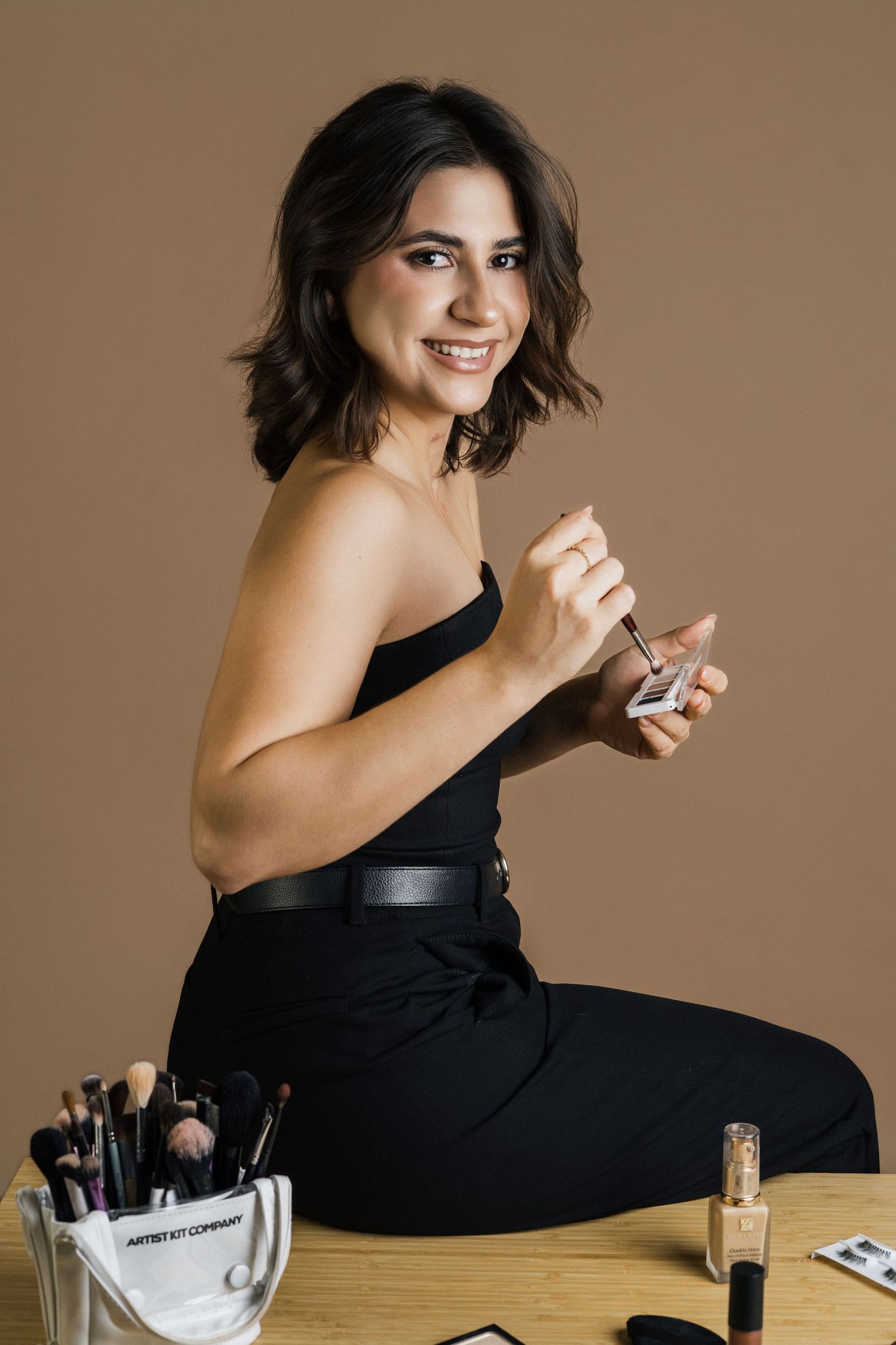 Artistic portrait series in black dress against warm brown background.