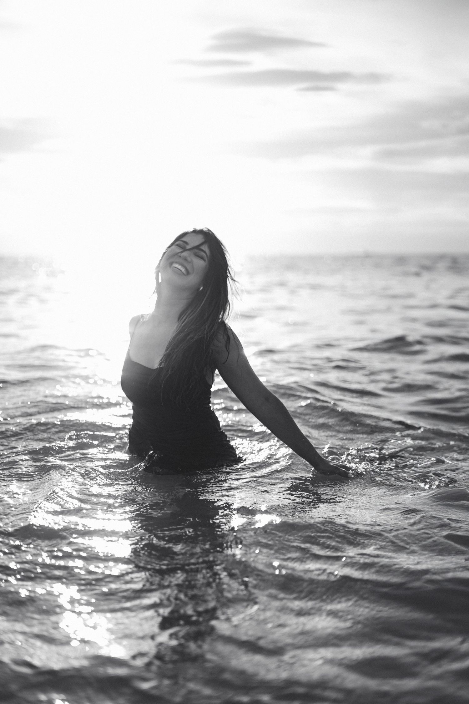 Dramatic black and white photo of person in water during sunset photoshoot.