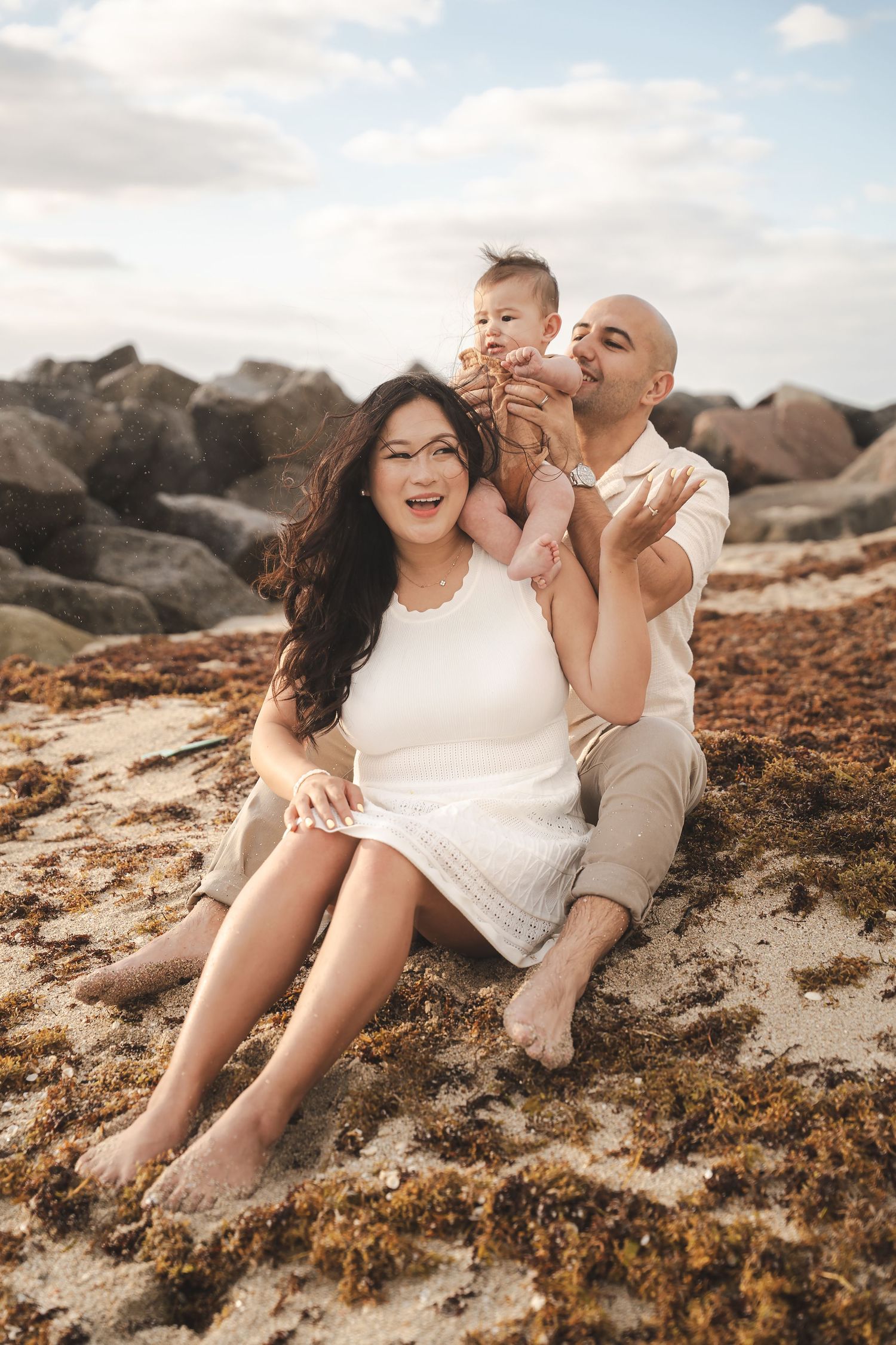 Couple sharing a joyful moment together on a rocky beach at sunset.