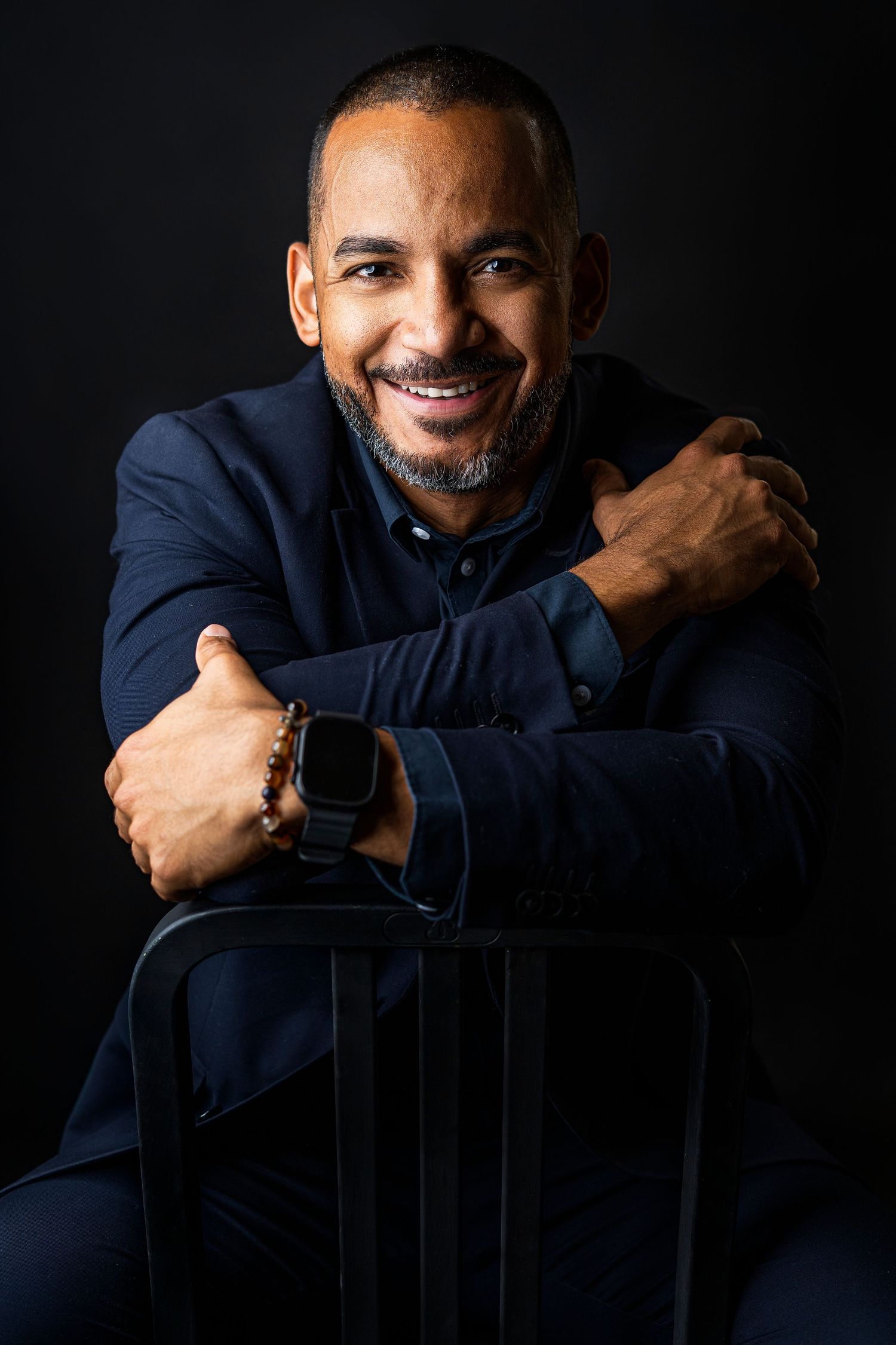 Portrait series in navy blue sweater against dark background showing genuine smiles.