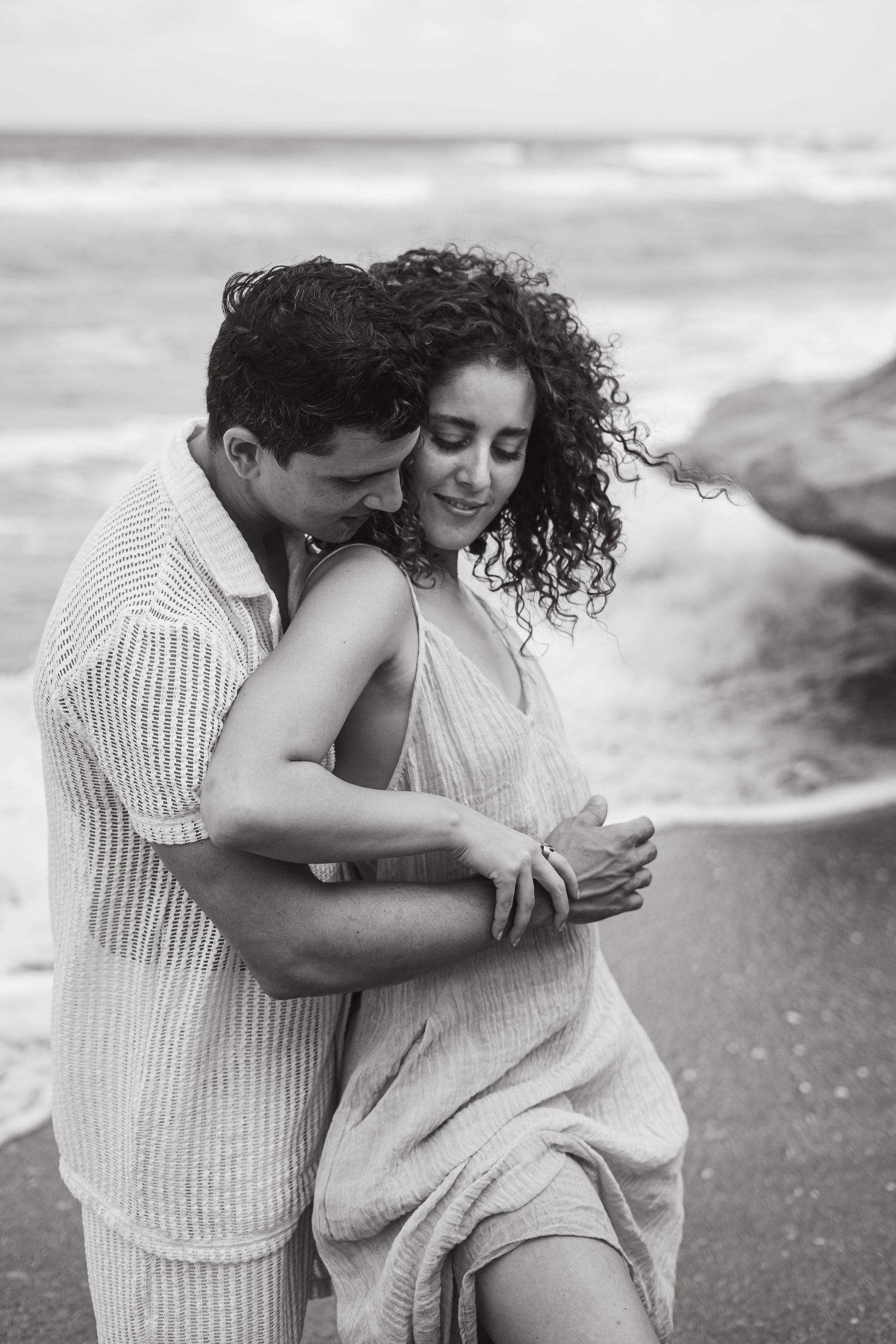 Black and white photos of a couple embracing on a beach.