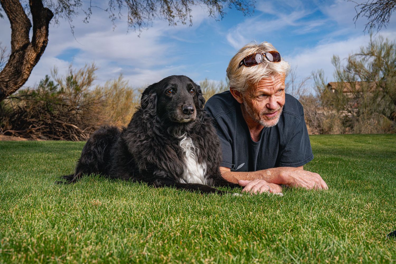 Lifestyle 'People and Pups' portrait of a dog owner and his best friend relaxing together in a grassy park in Phoenix.