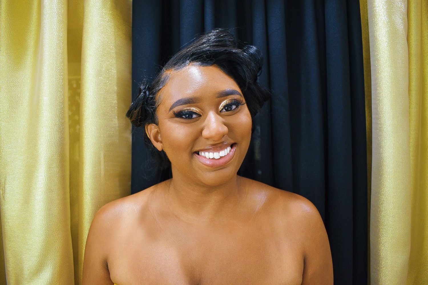 Portrait against yellow and navy curtains showing bright smile and natural makeup.