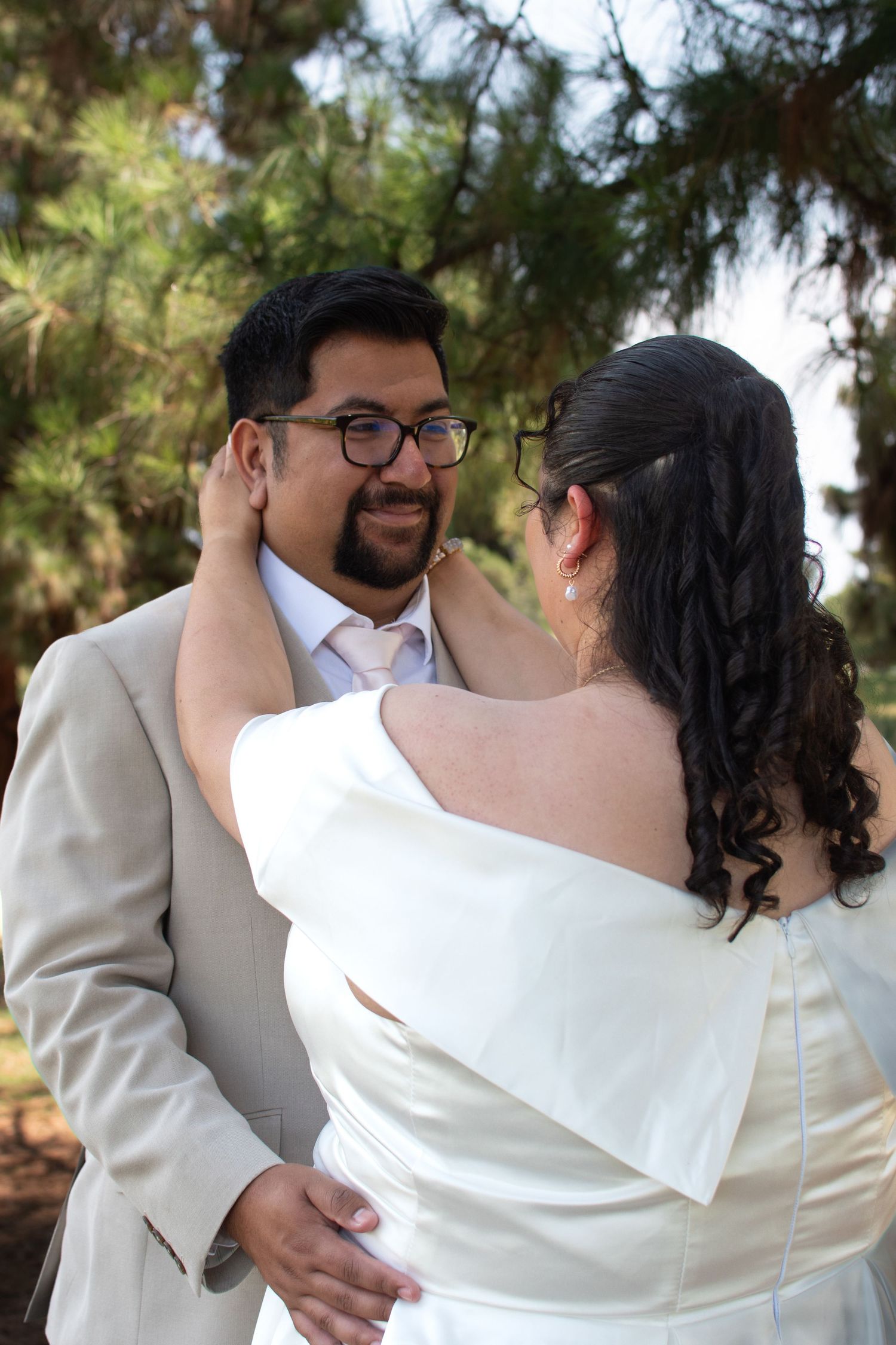 Wedding couple in matching ivory and beige outfits embrace during their outdoor photo session.