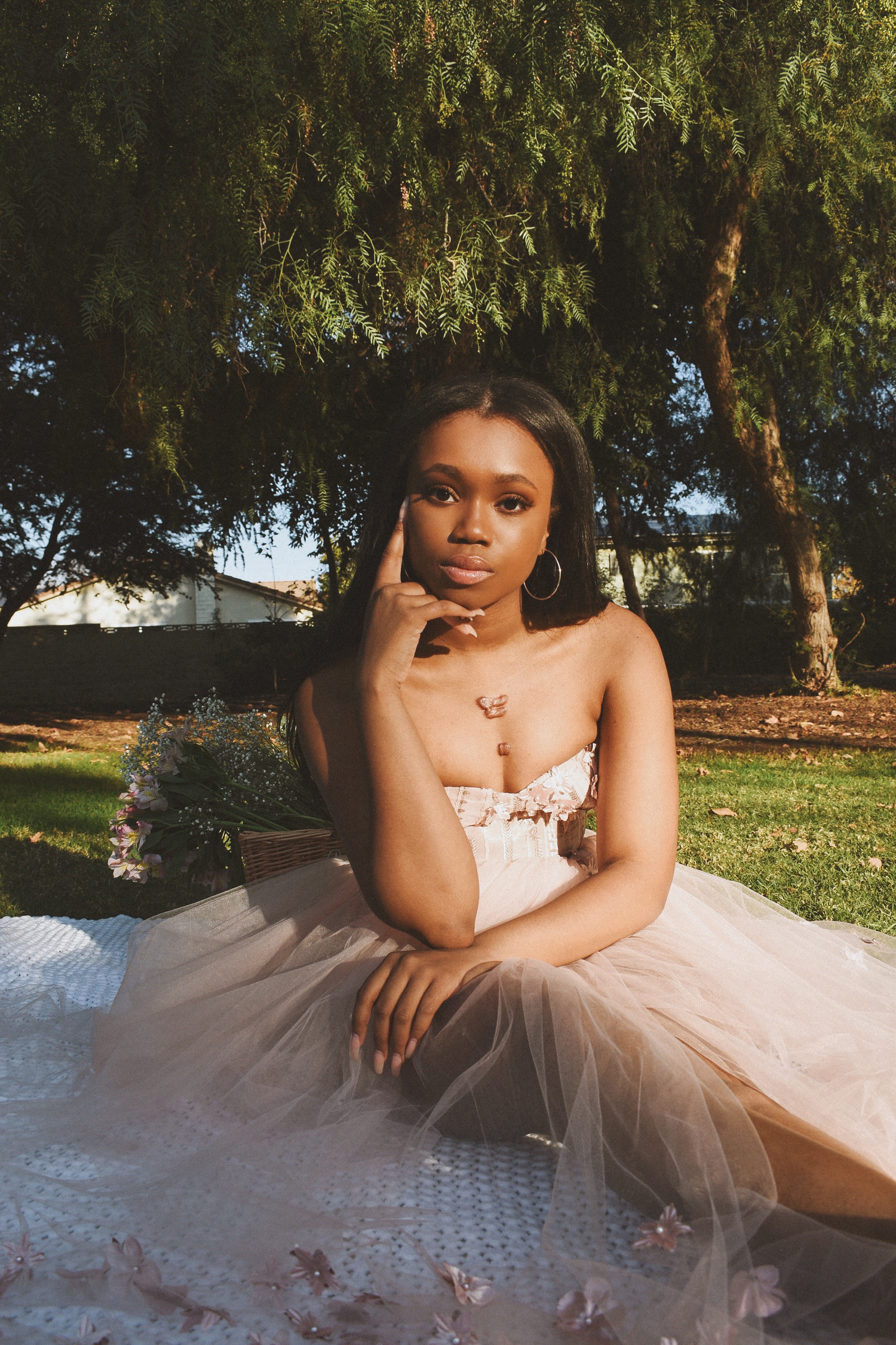 Elegant portrait featuring a strapless gown with tulle skirt in an outdoor garden setting.