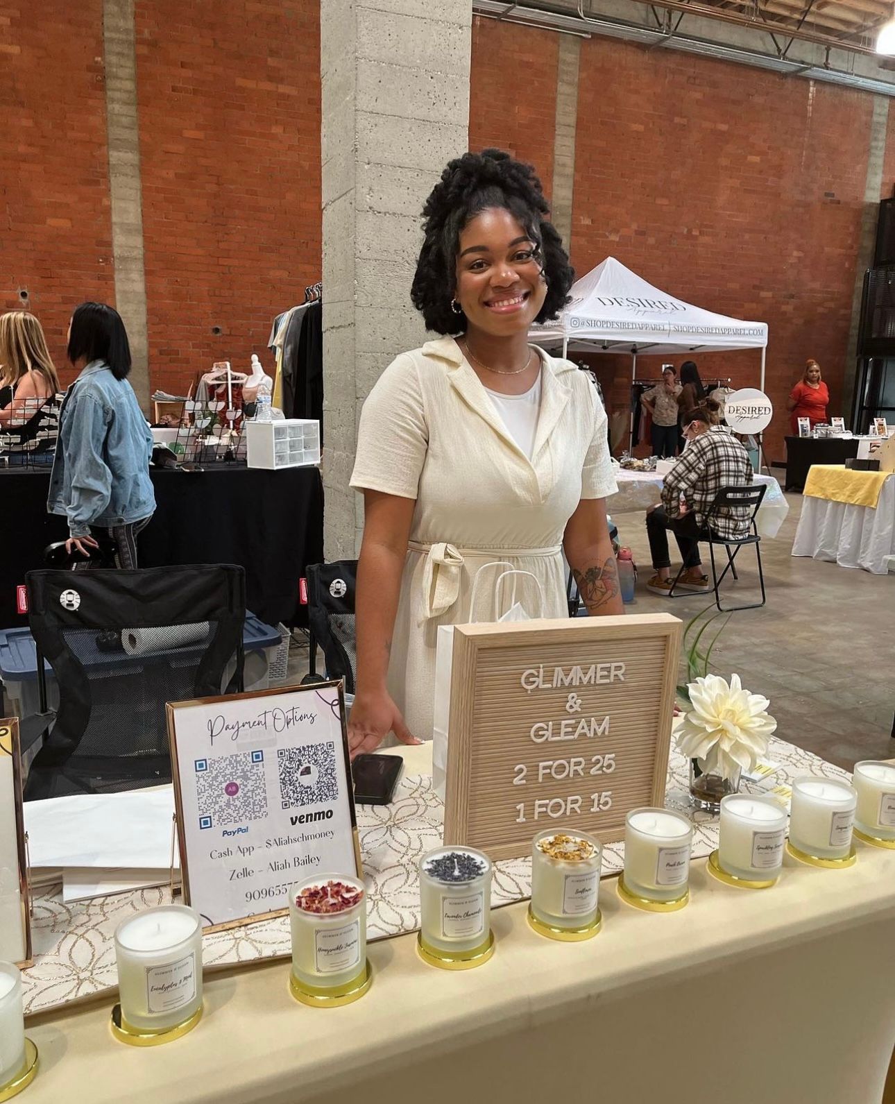 A small business owner displays candle products at a craft market vendor booth.