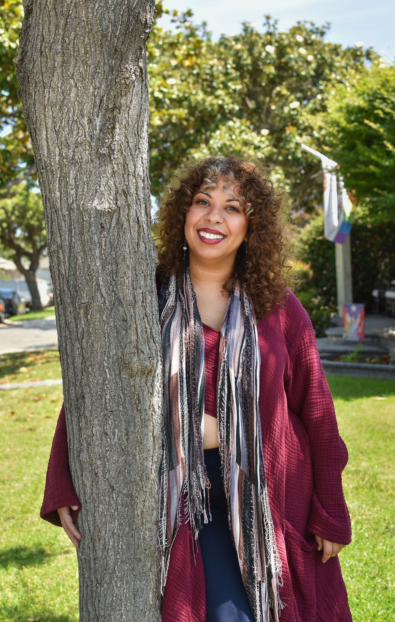 A series of outdoor photos showing a person in a burgundy cardigan and striped scarf posing by a tree on a sunny day.