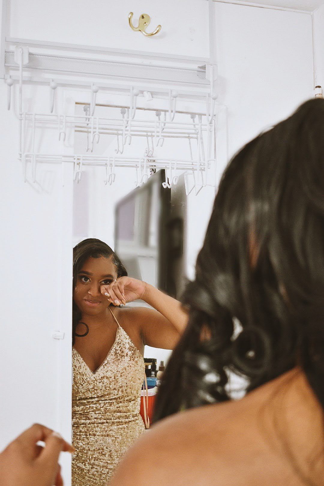 A sparkling gold sequin dress reflected in a mirror during a formal preparation.