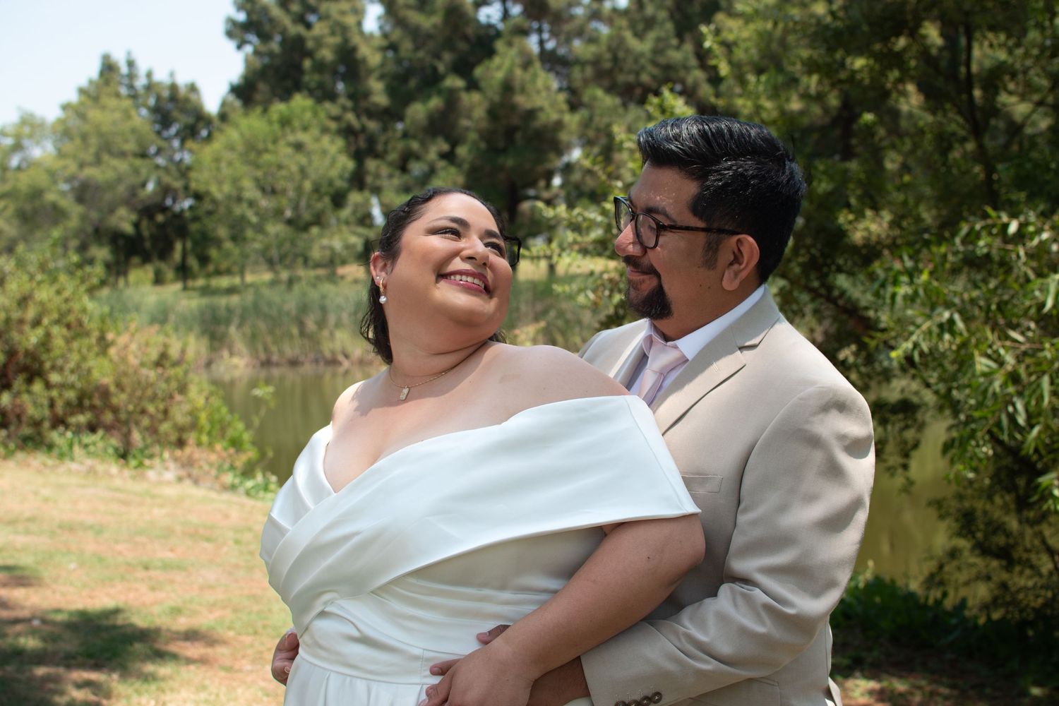 A couple shares joyful, candid moments while dancing together in a sun-dappled outdoor setting.