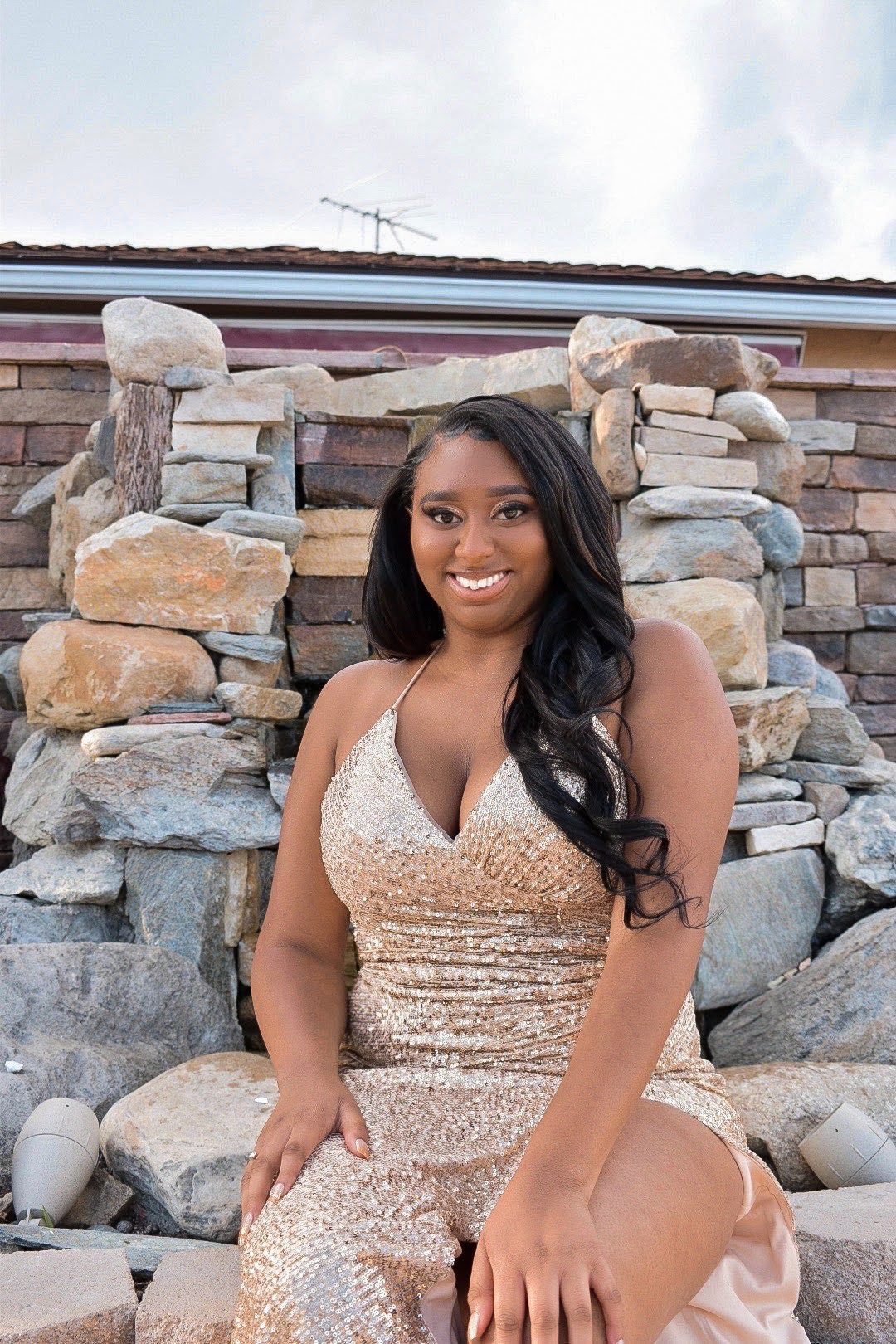 Beautiful portrait against rustic stone wall wearing sparkling champagne gown.